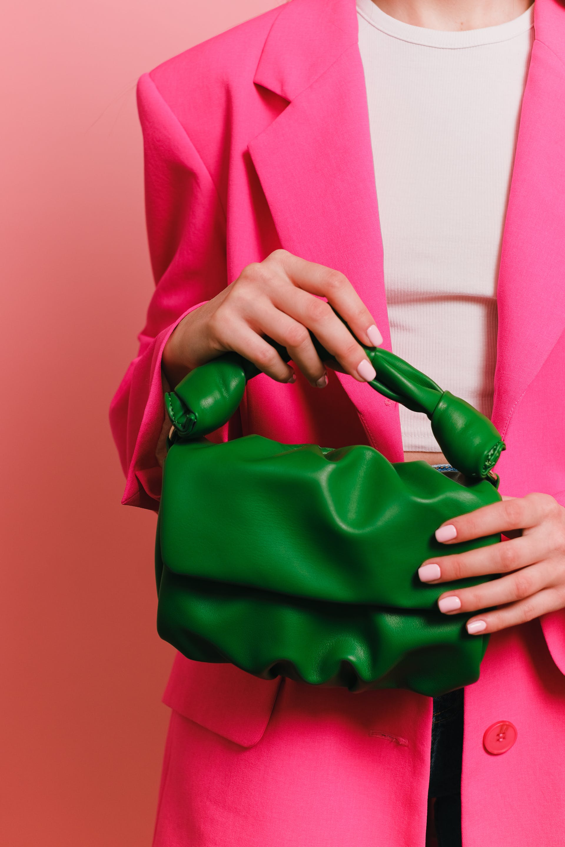 Woman in a pink blazer holding a green handbag | Source: Pexels