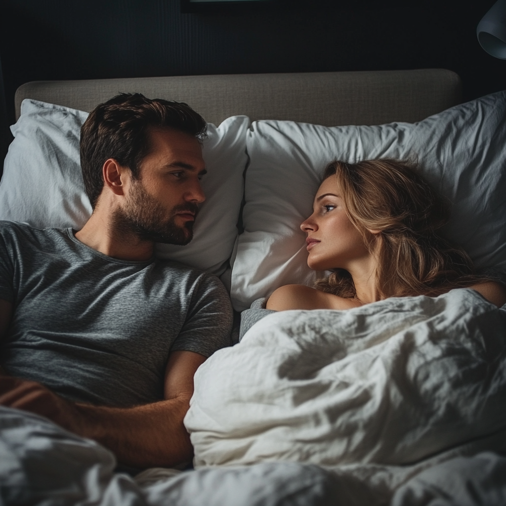 A man and woman looking at each other in bed | Source: Midjourney