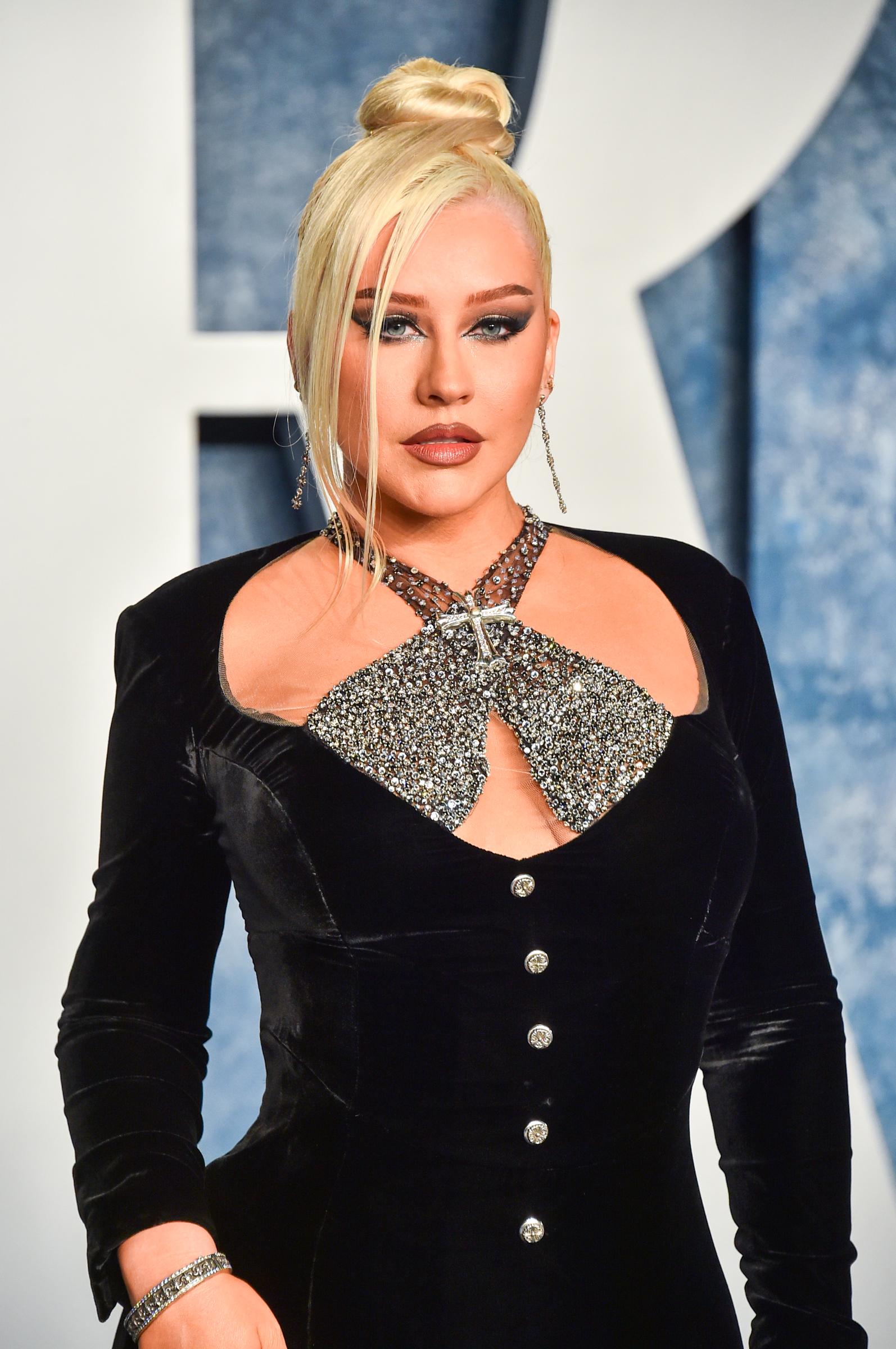 Christina Aguilera arrives at the 2023 Vanity Fair Oscar Party at the Wallis Annenberg Center for the Performing Arts in Beverly Hills. She wears a velvet black gown with crystal embellishments across the bodice and halter neckline, styled with a sleek topknot and dramatic eyeliner, highlighting her continued embrace of high-impact red carpet glamour.