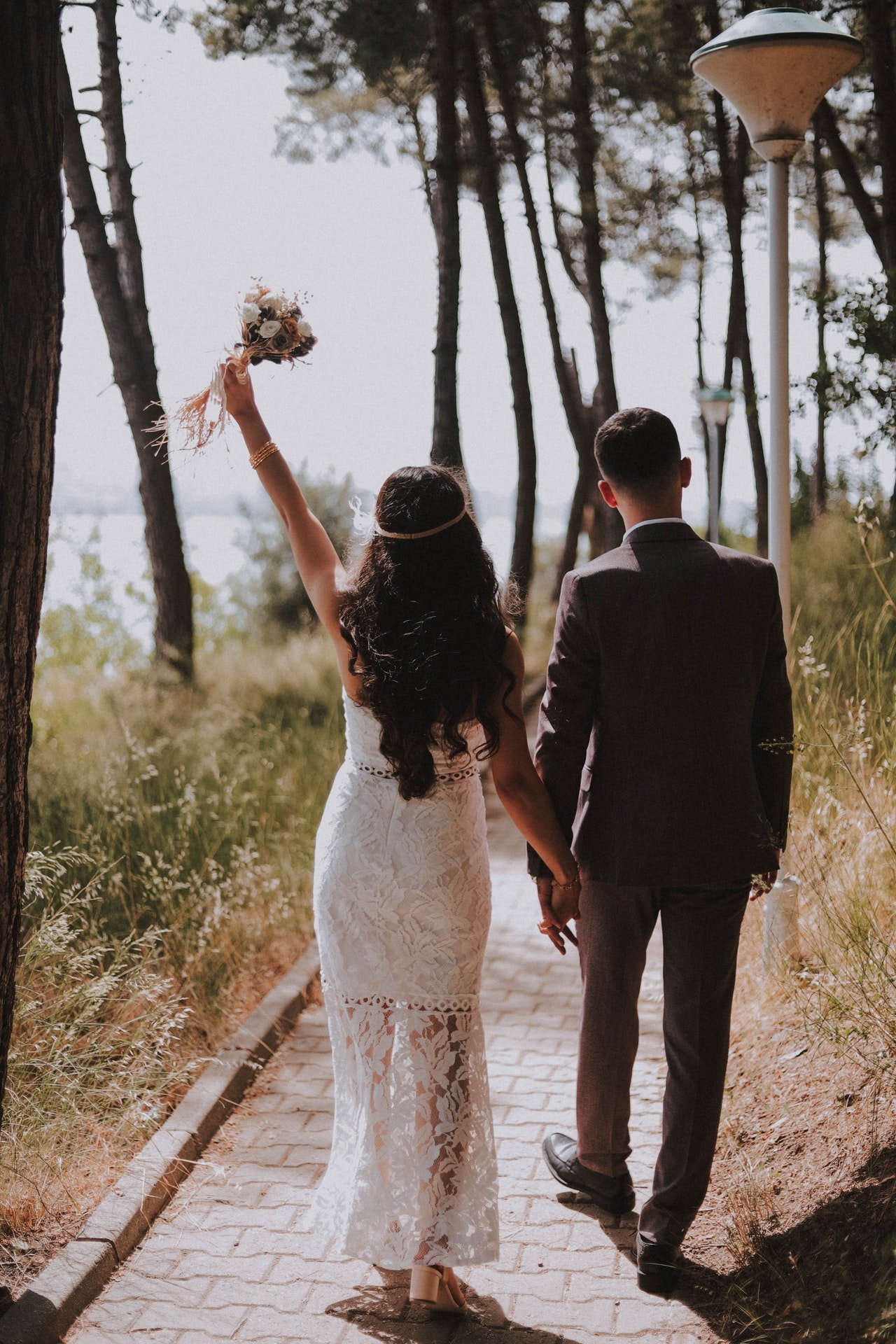 A couple walking in the woods in their wedding outfits. | Photo: Pexels