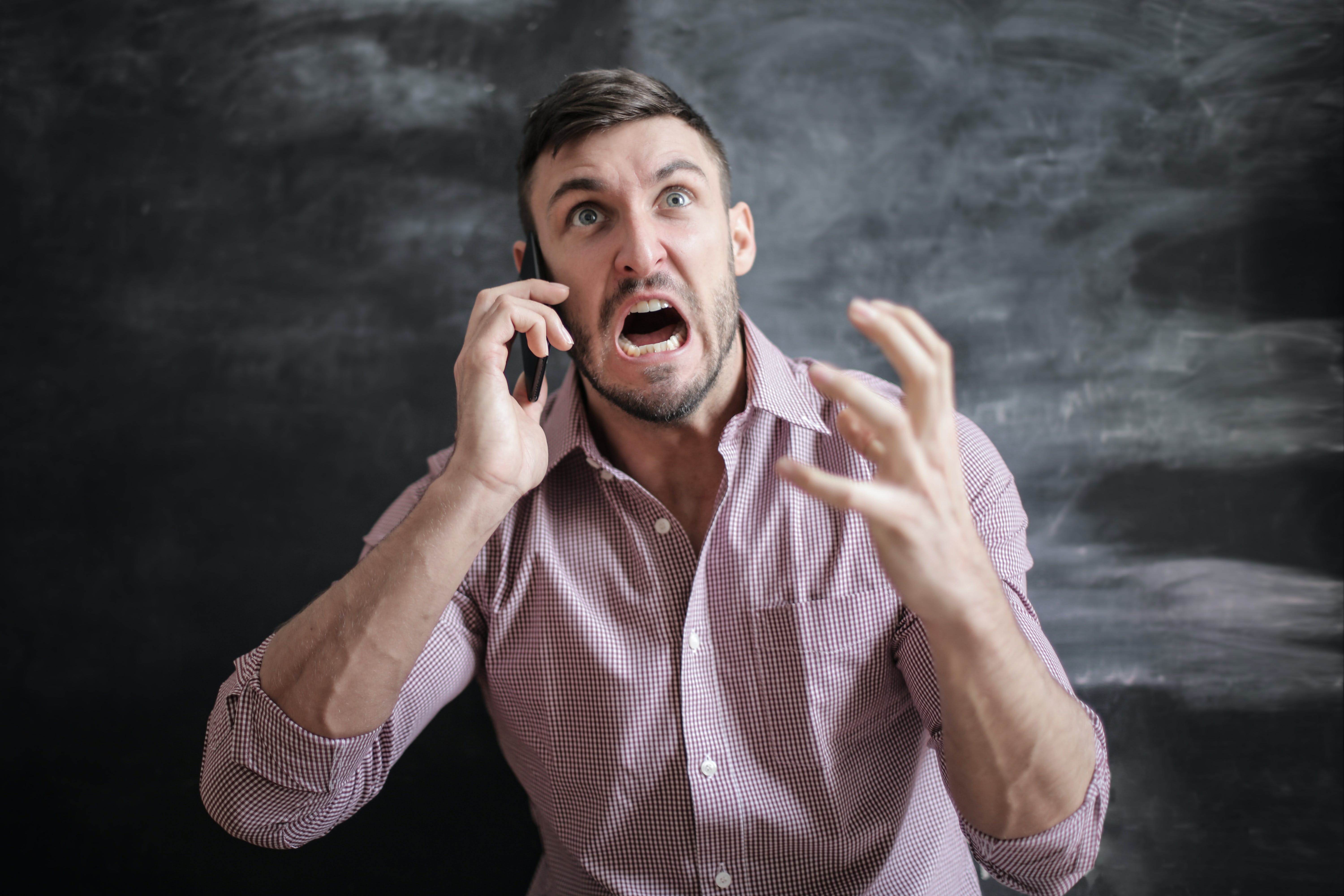 A man shouts while angrily gesturing during a phone call | Source: Pexels