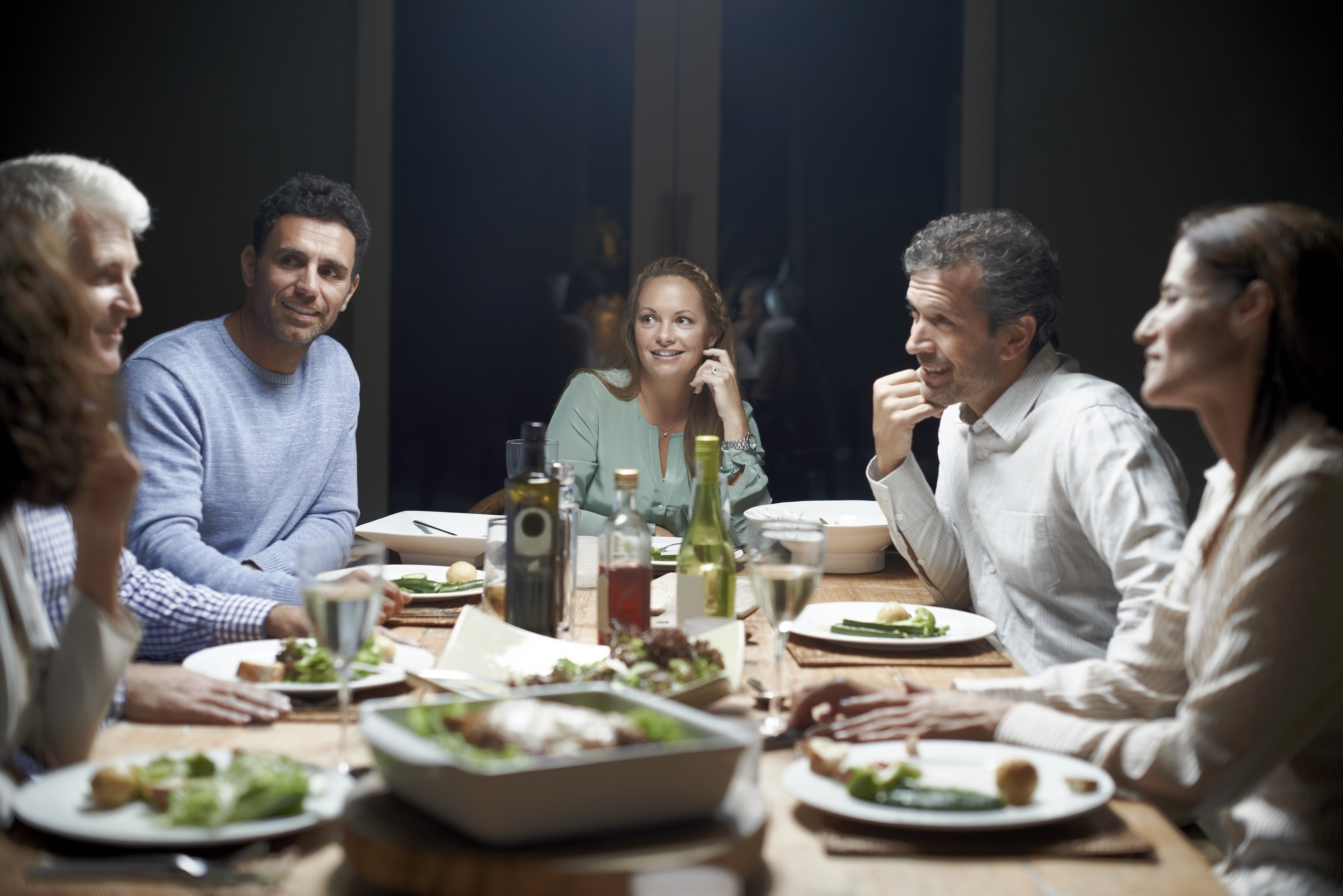 Friends communicating while having dinner at table | Source: Getty Images