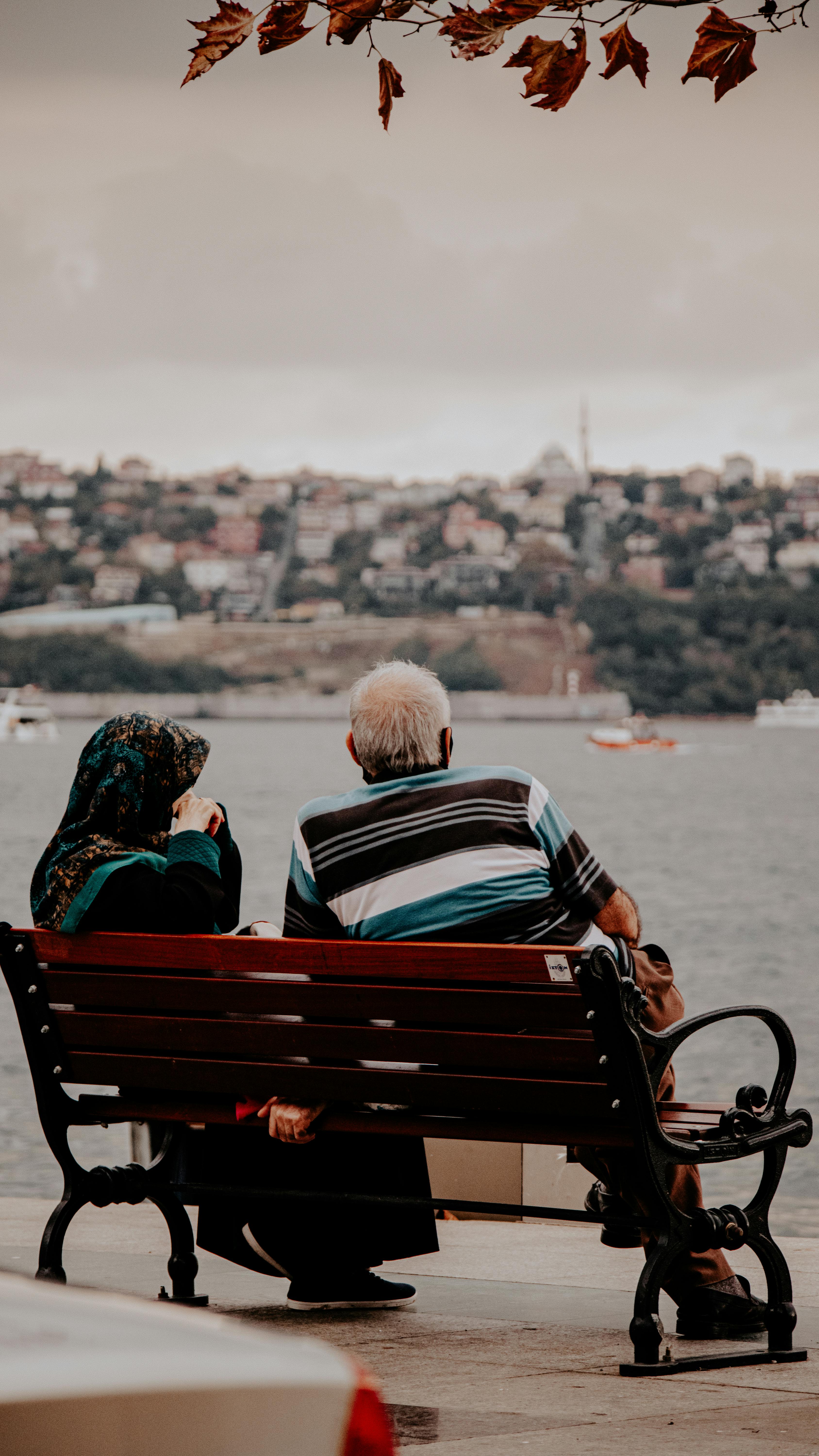 A middle-aged couple sitting on a bench overlooking water | Source: Pexels