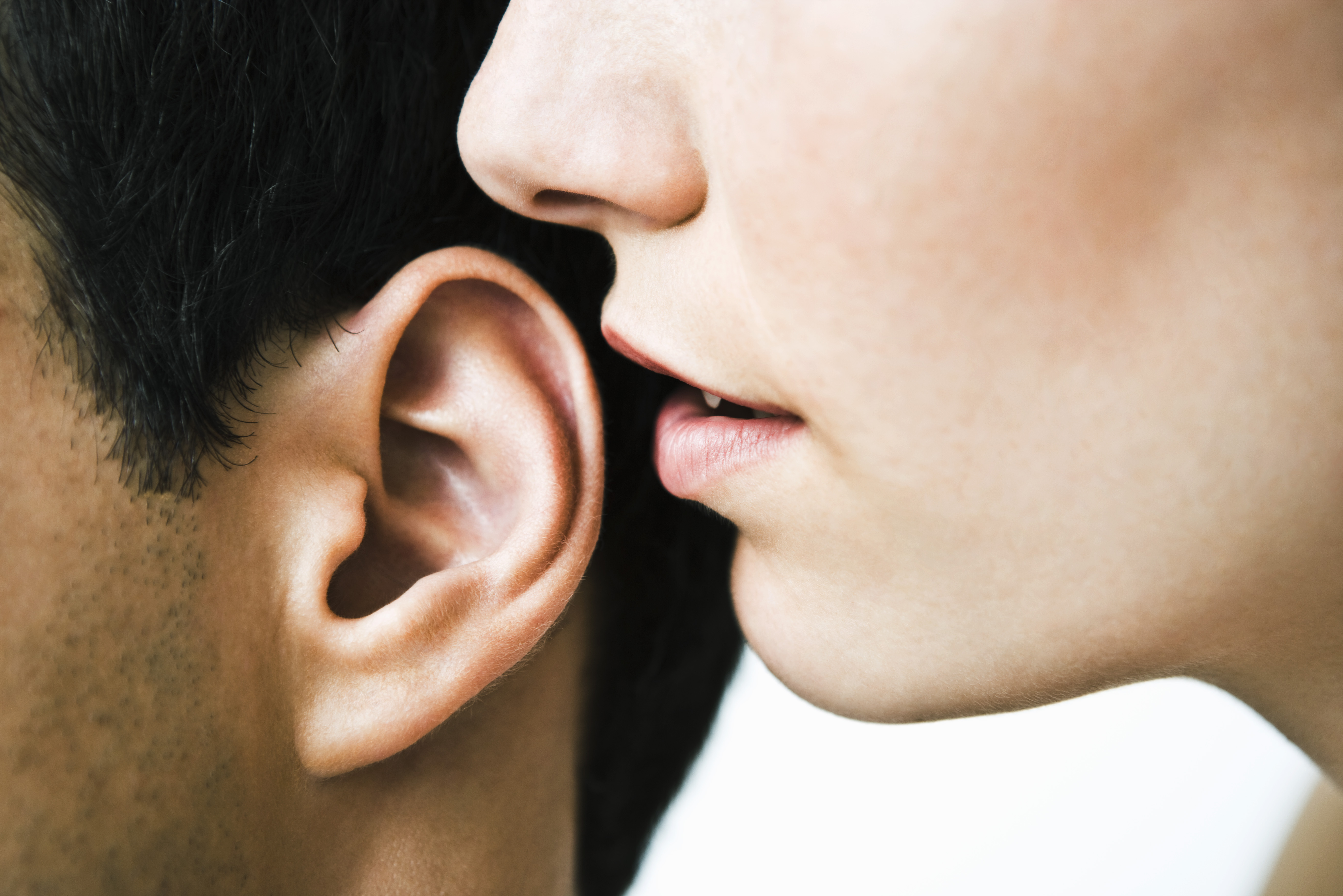 Woman whispering in man's ear, close-up | Source: Getty Images