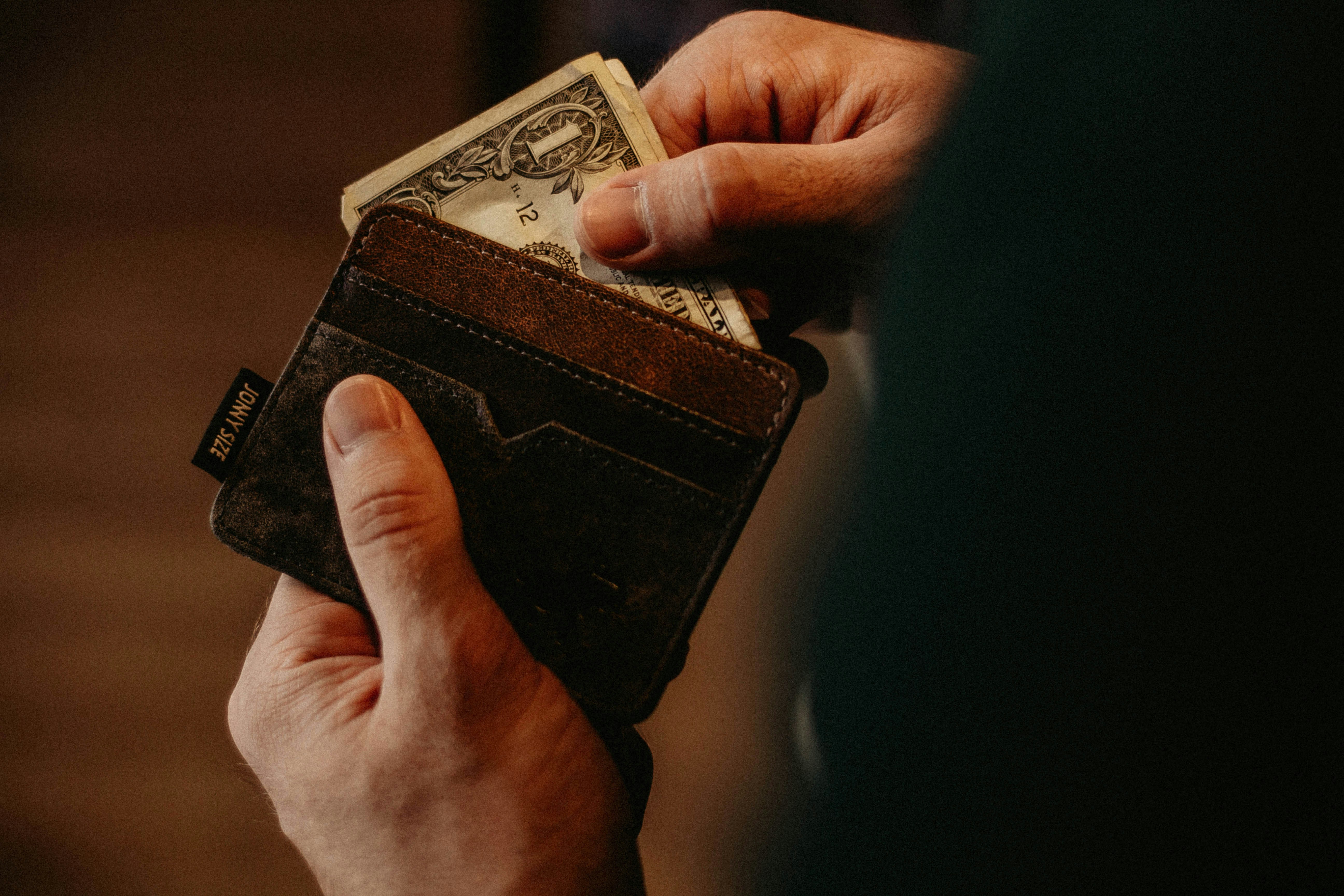 A person pulling out cash from their wallet | Source: Unsplash
