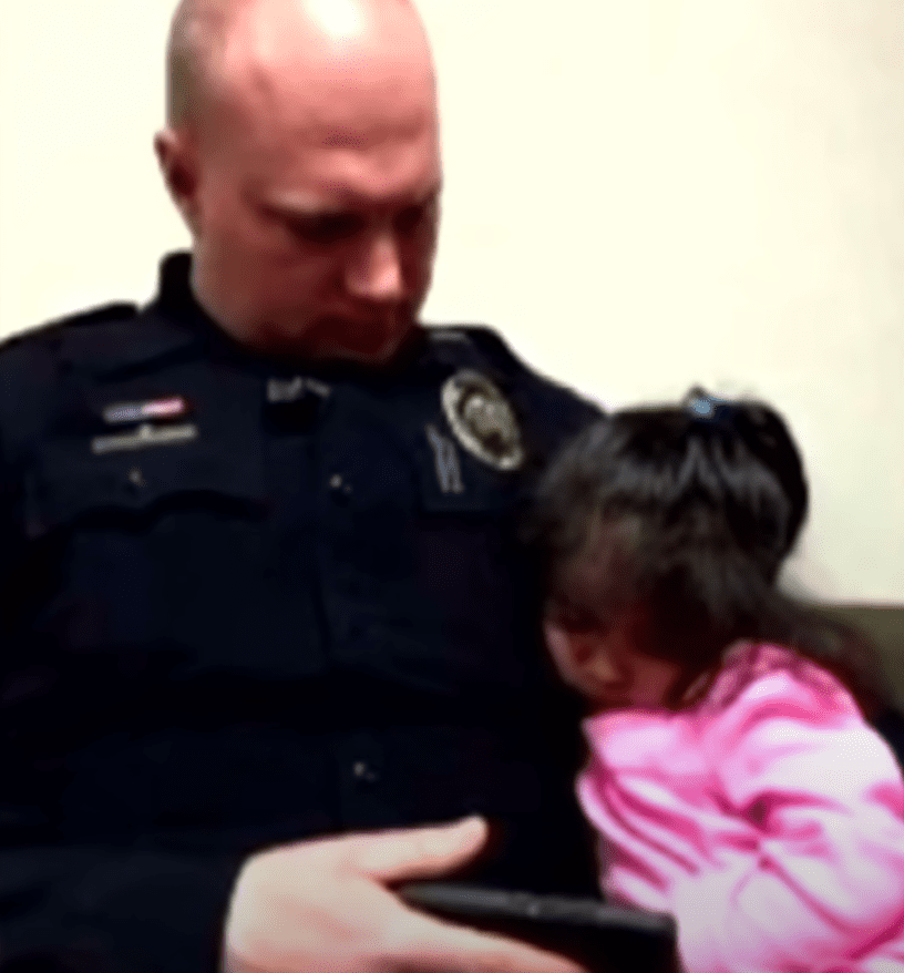 Officer Kevin Norris keeps a little girl occupied with cartoons on his phone. | Source: youtube.com/Inside Edition 