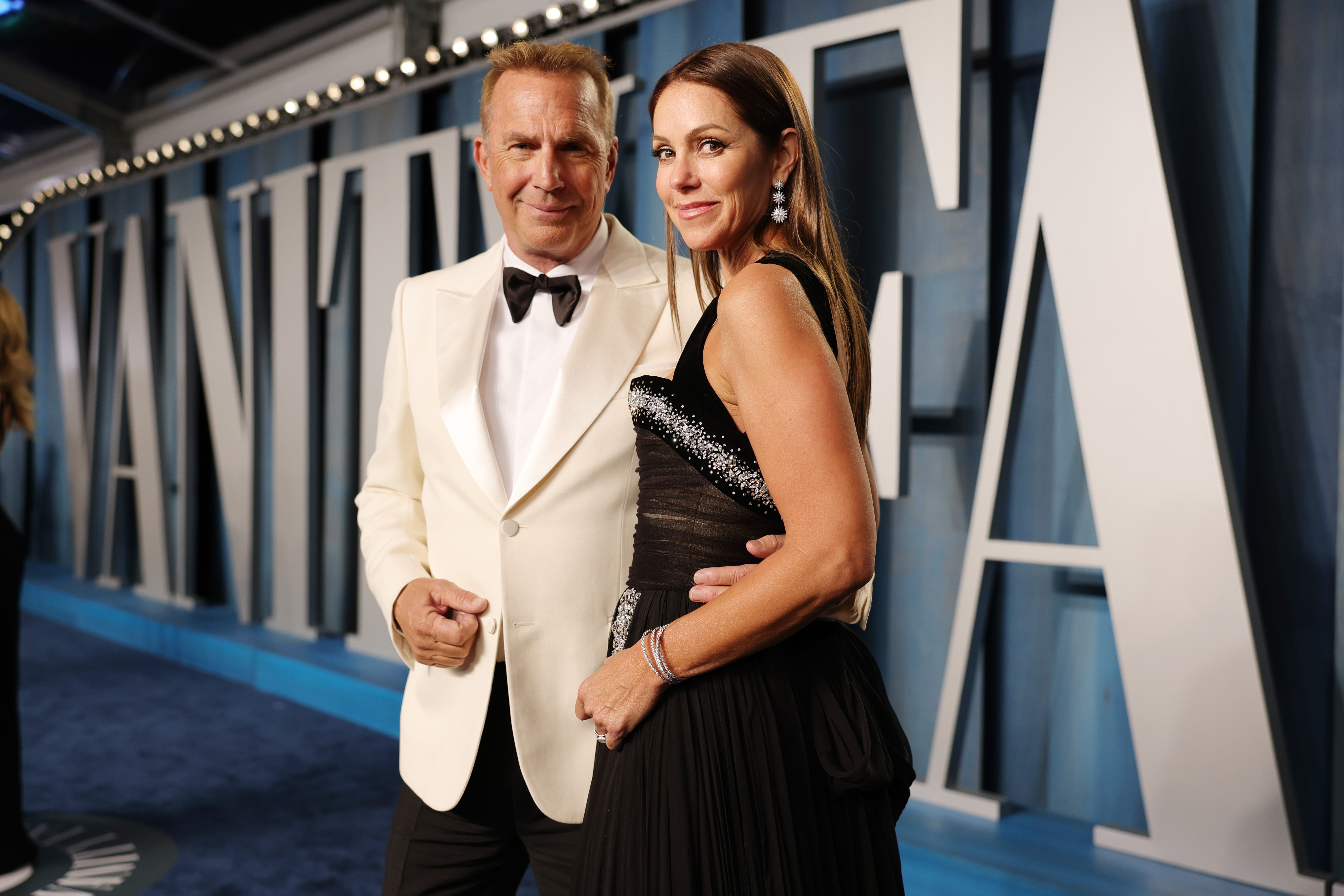Kevin Costner and Christine Baumgartner made a glamorous appearance at the Vanity Fair Oscar Party, with Costner in a crisp white tux and Baumgartner stunning in a sparkling black gown. Arm in arm, the longtime couple looked effortlessly poised under the bright lights.