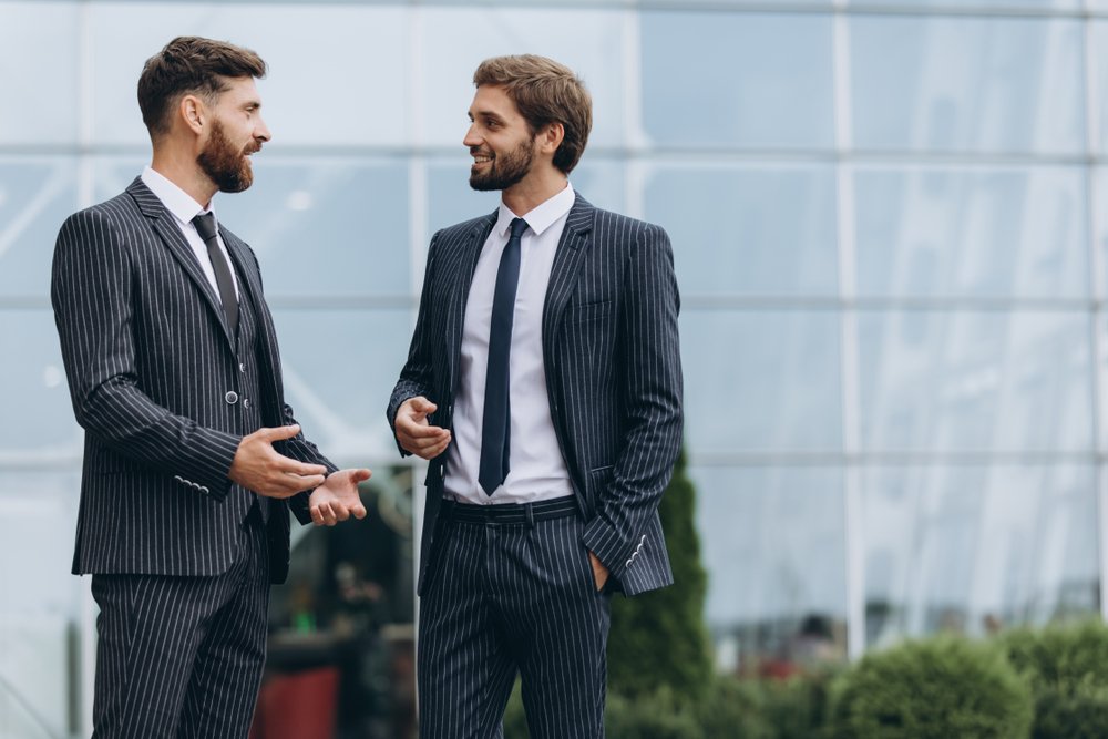 Two young men discussing outside an office building. | Photo: Shutterstock.