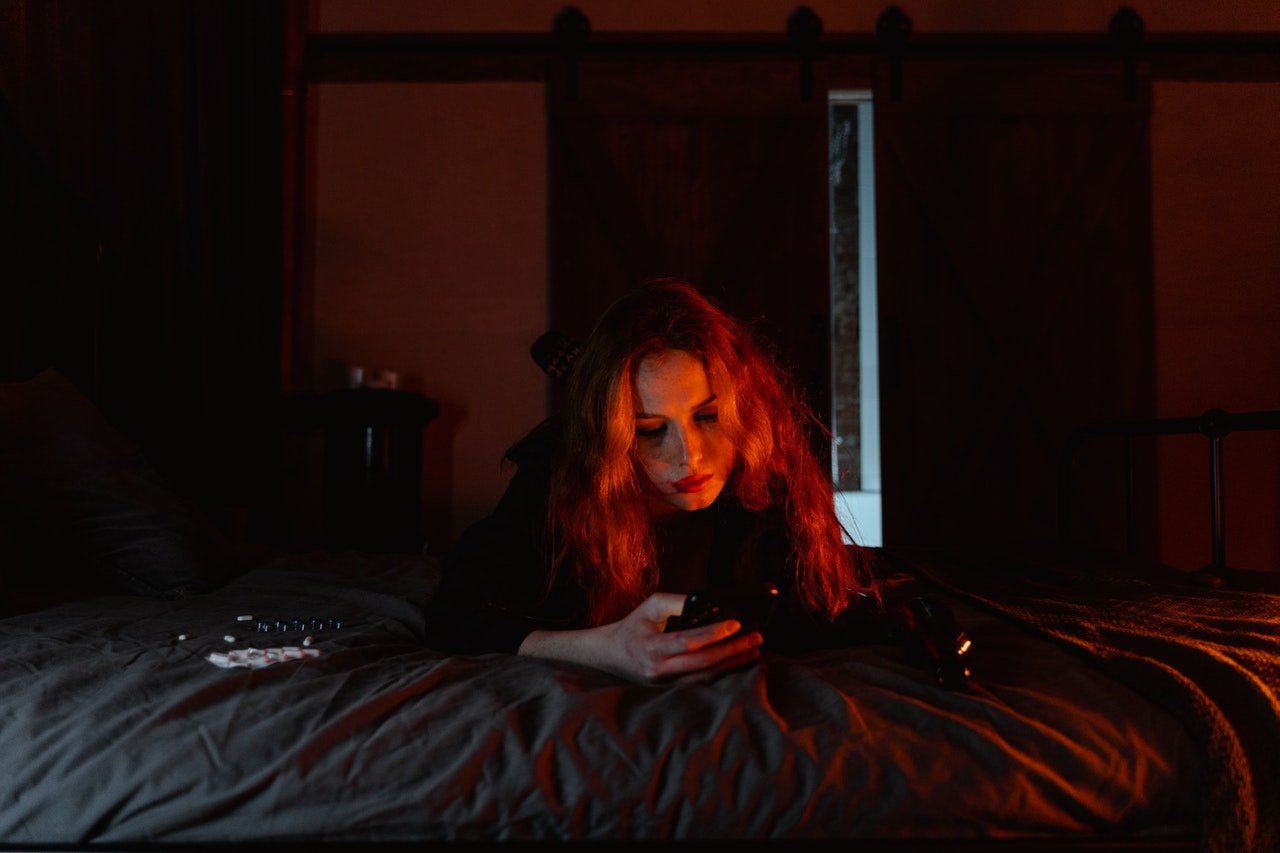 Woman using phone in the dark | Source: Pexels