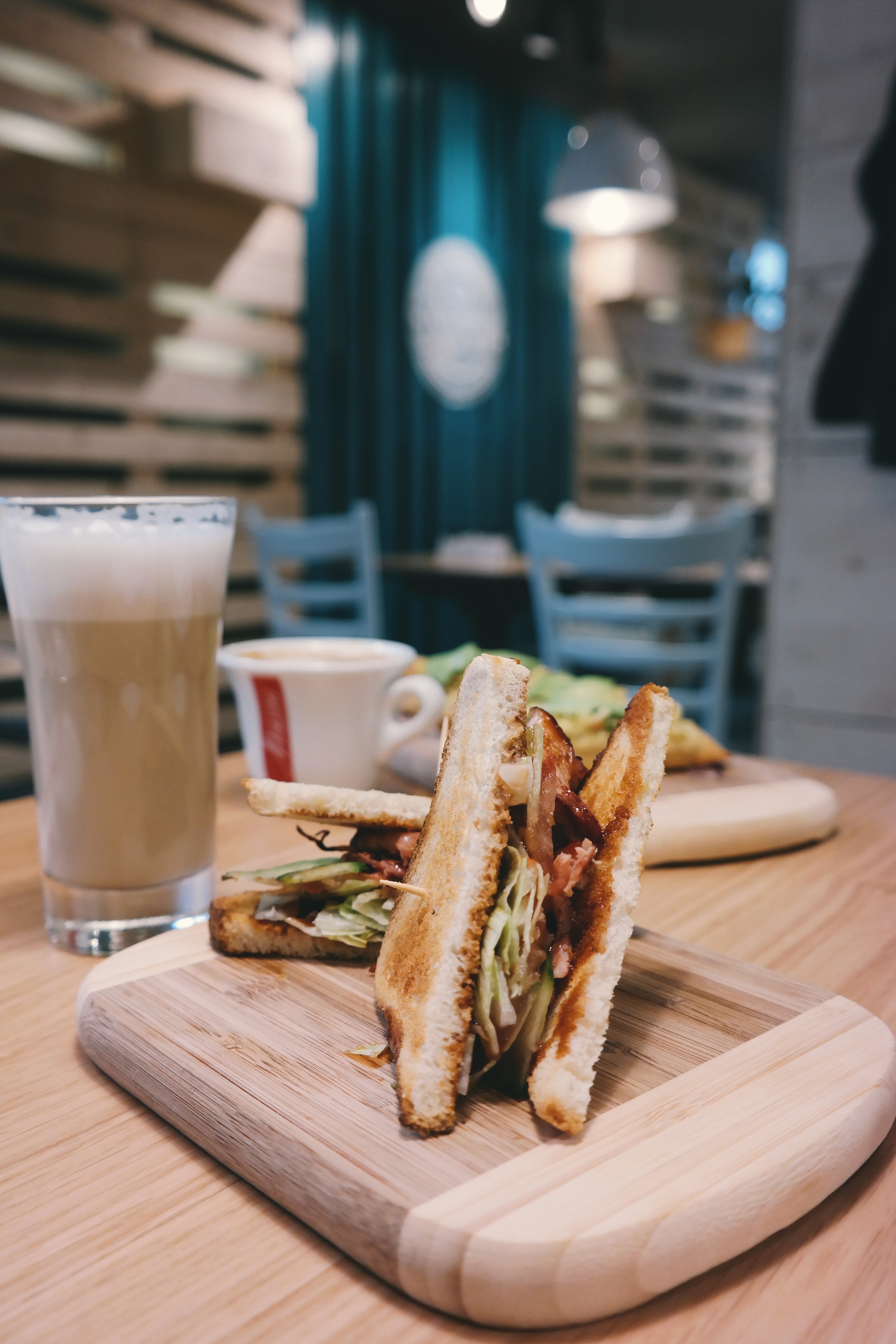 A drink and a couple of sandwiches on a dining table. | Photo: Pexels