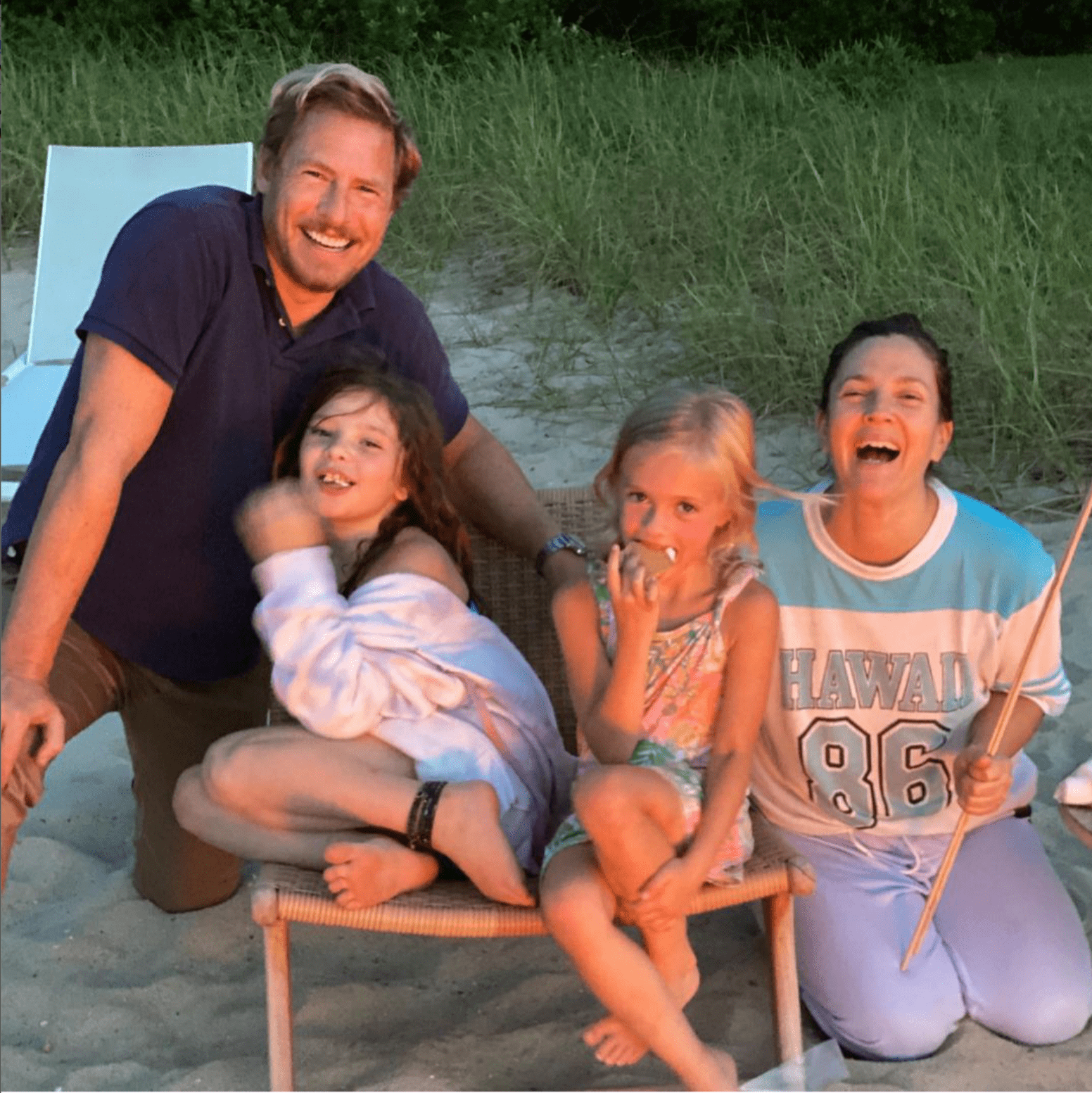 Drew Barrymore, Will Kopelman, Frankie, and Olive huddling together while making s'mores near a fire. | Photo: Instagram/Drew Barrymore
