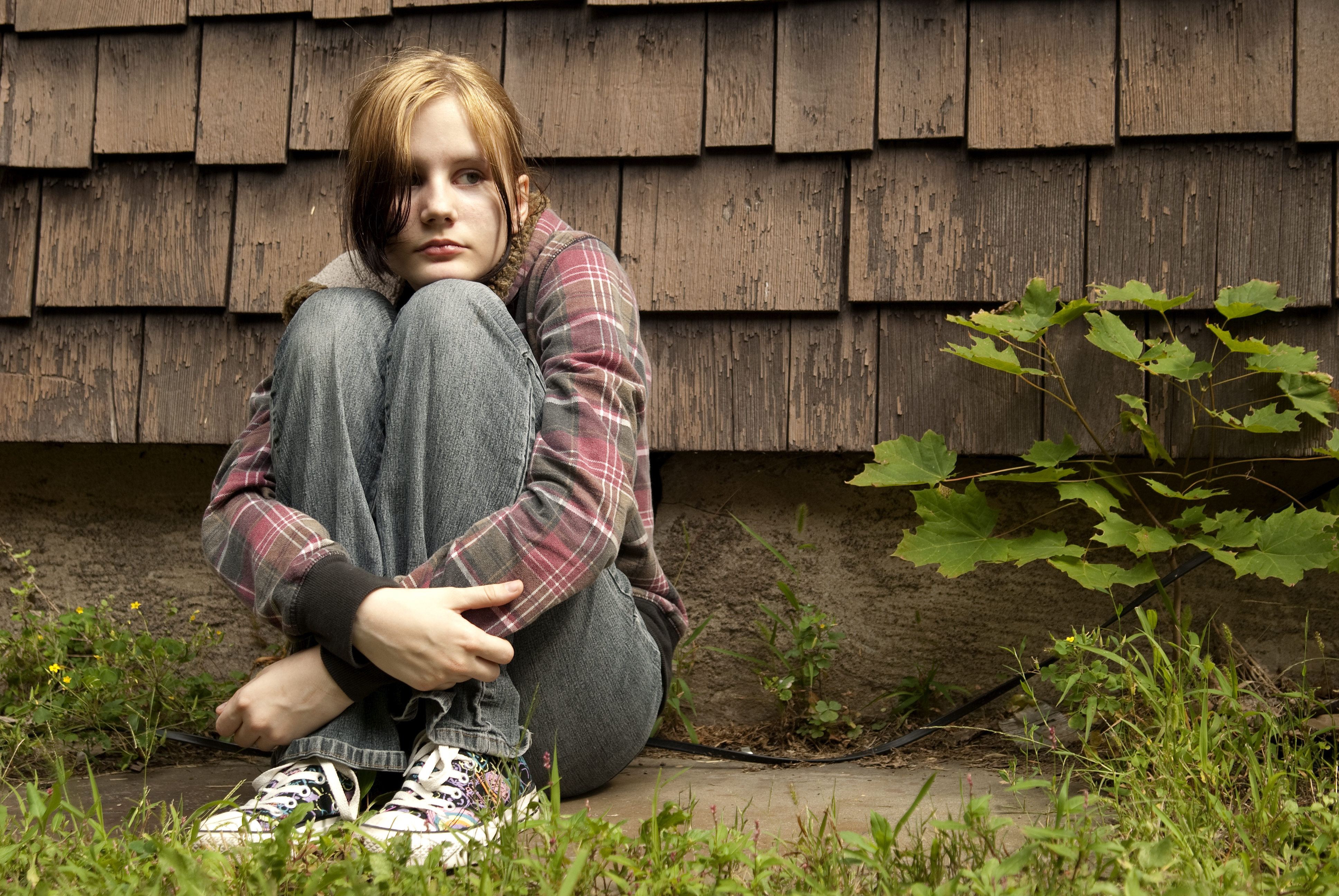 Ein trauriges Mädchen sitzt auf dem Boden | Quelle: Shutterstock