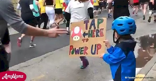 Little boy motivates marathon runners with a Super Mario tap card