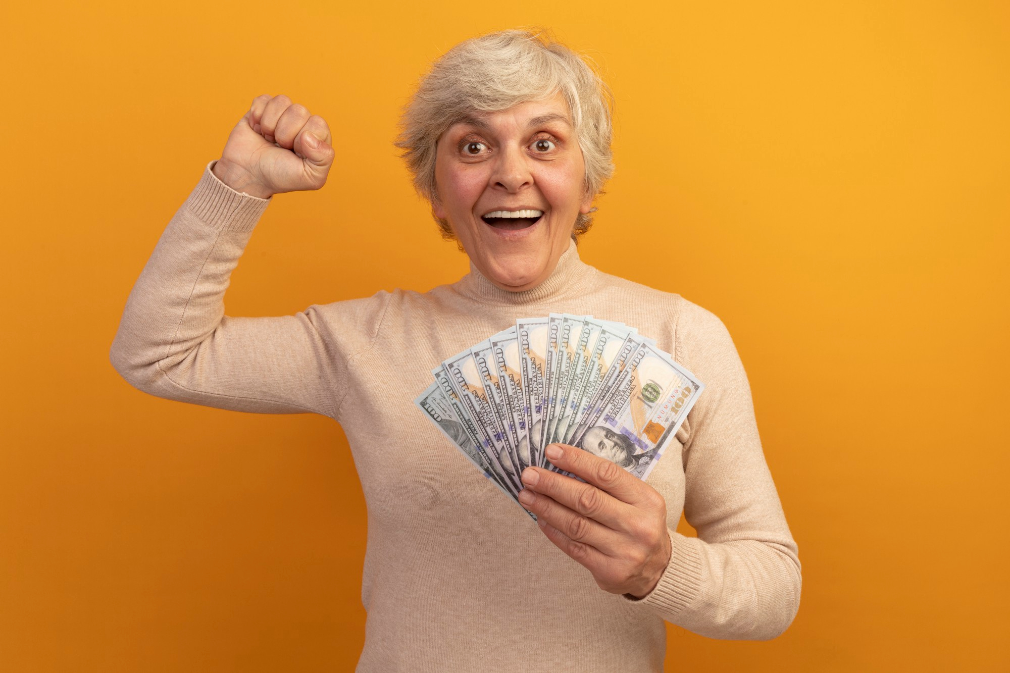 A middle-aged woman celebrating while holding money in one hand | Source: Freepik
