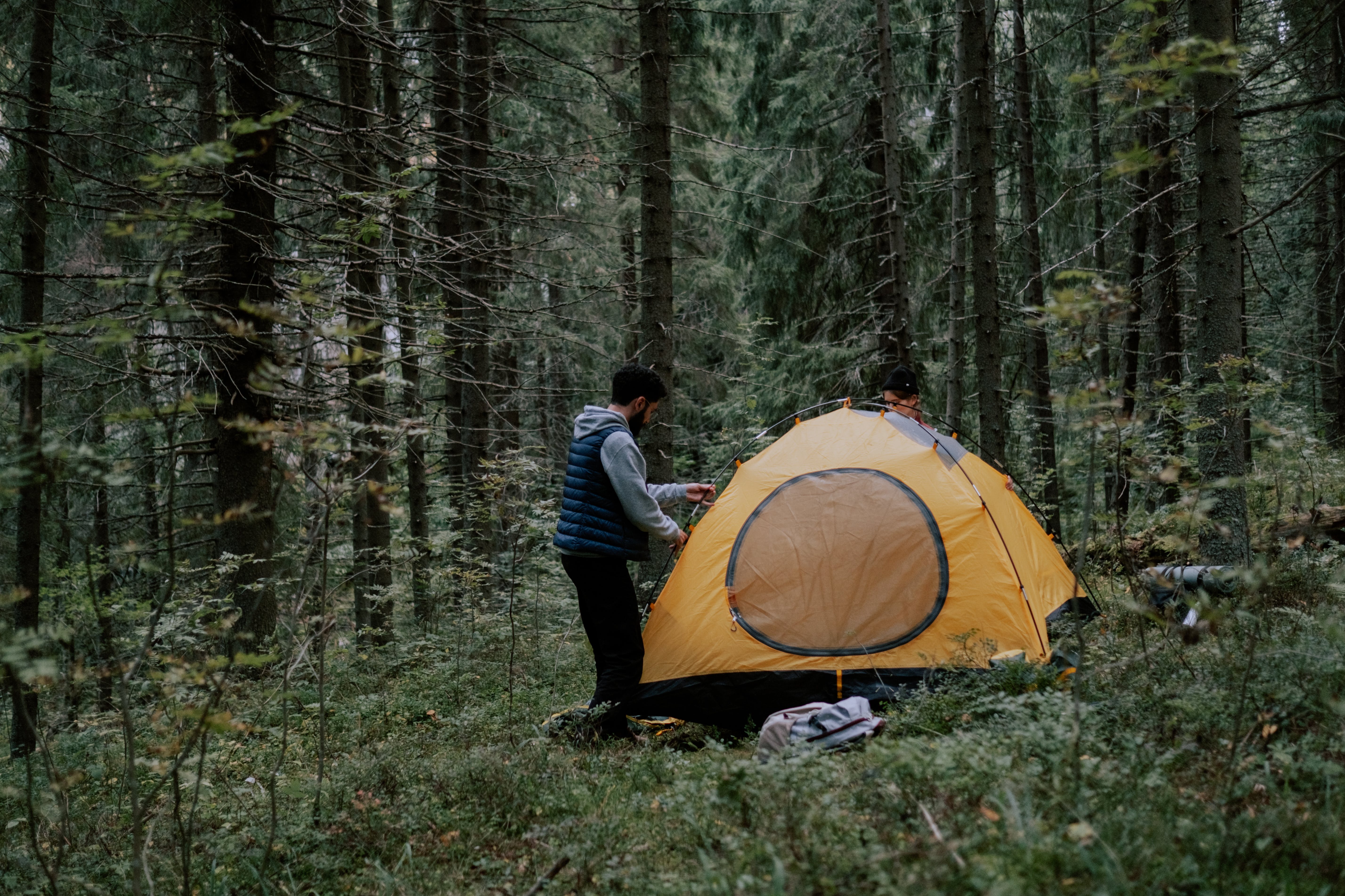 A man putting up his tent in the forest | Source: Pexels