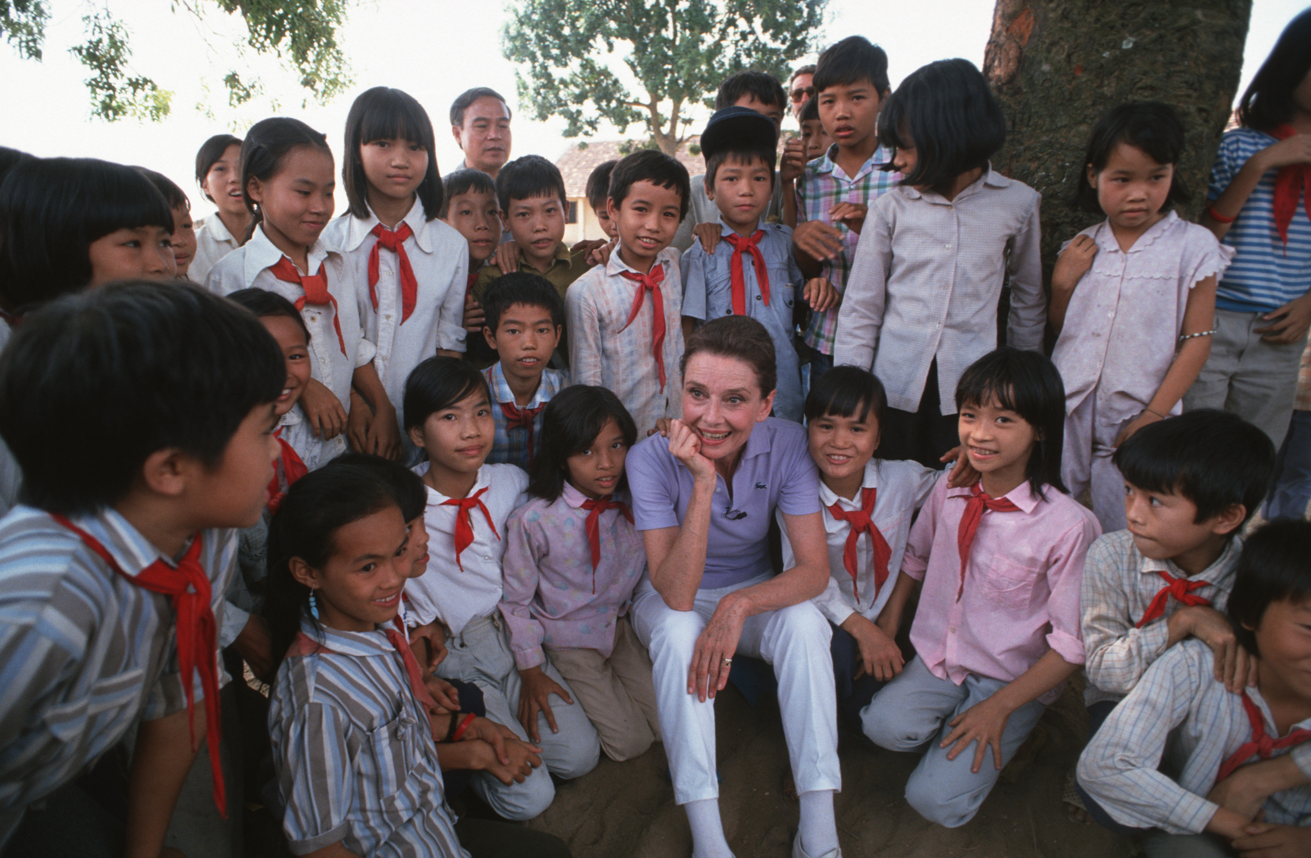 Audrey Hepburn takes time to get to know some schoolchildren in uniform in a small village close to Hanoi on October 1, 1990 | Source: Getty Images