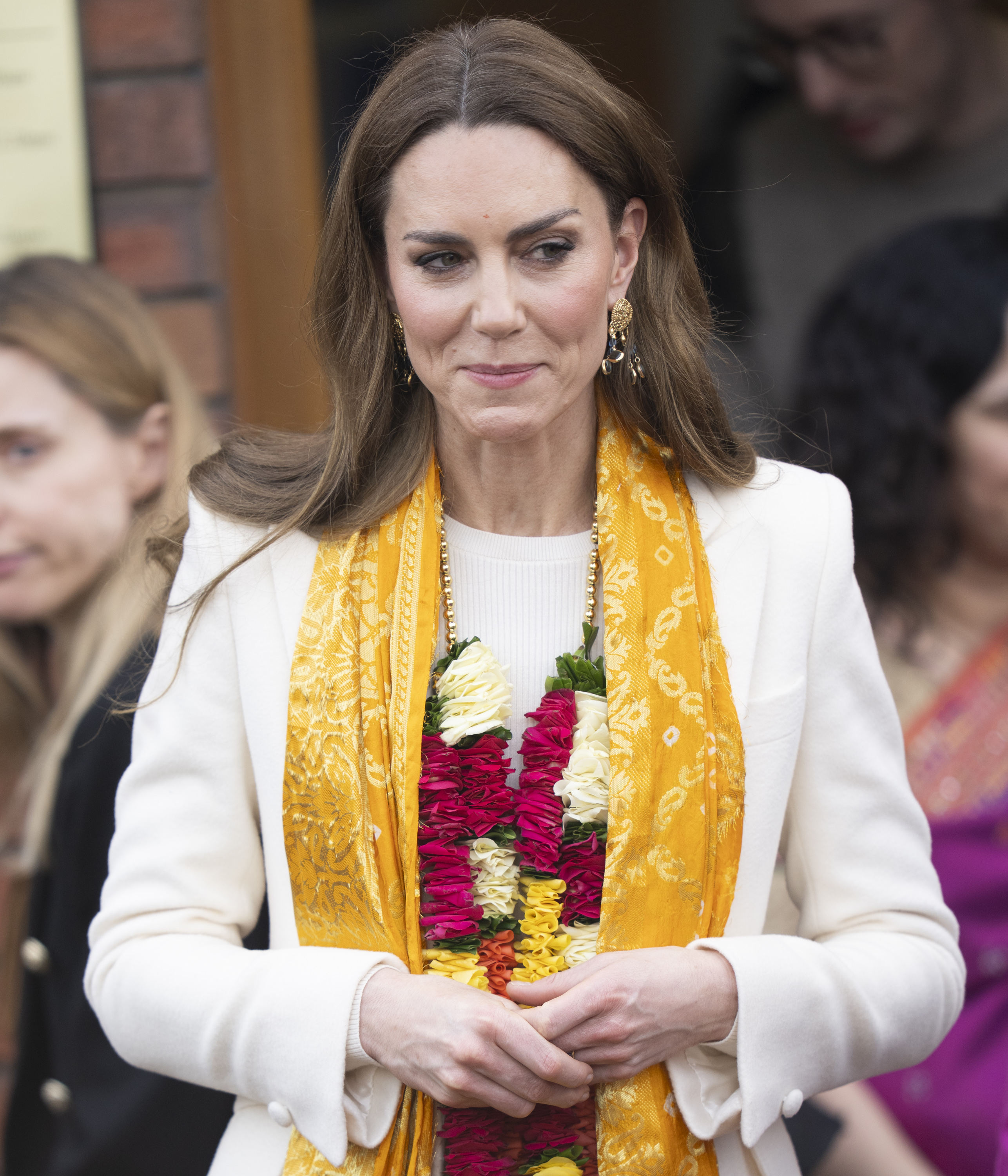 Catherine, Princess of Wales, departs Shreeji Dham Haveli Hindu temple in Leicester, England, on March 5, 2026, following her visit to the Hindu temple. Wearing a vibrant flower garland and a golden ceremonial scarf draped over her cream ensemble, the Princess of Wales pauses briefly outside the entrance as members of the community gather nearby to watch her leave.