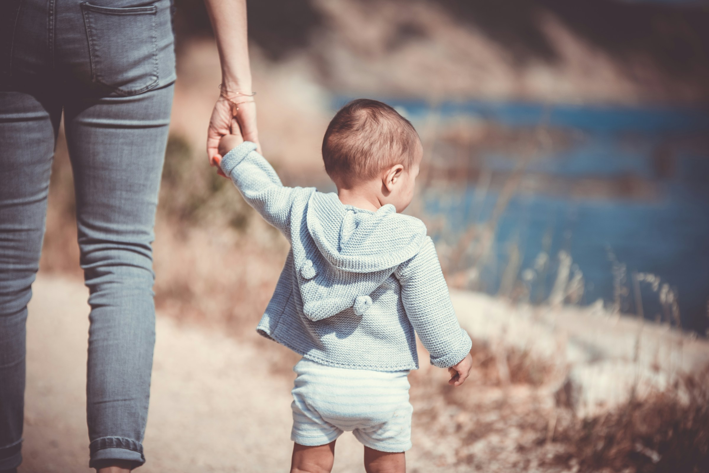 A woman holding a toddler's hand | Source: Unsplash