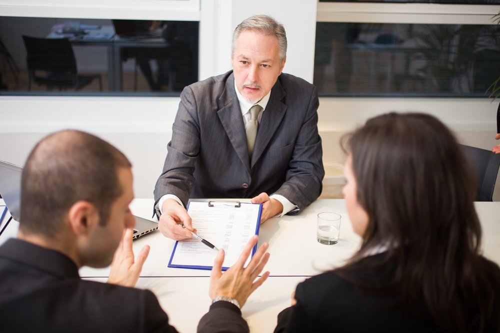A divorce lawyer attending to a couple in his office. | Photo: Shutterstock