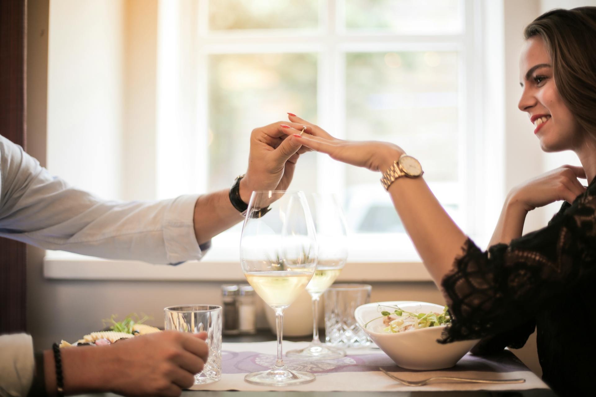 A close-up shot of a man sliding a ring on his girlfriend's finger during dinner | Source: Pexels
