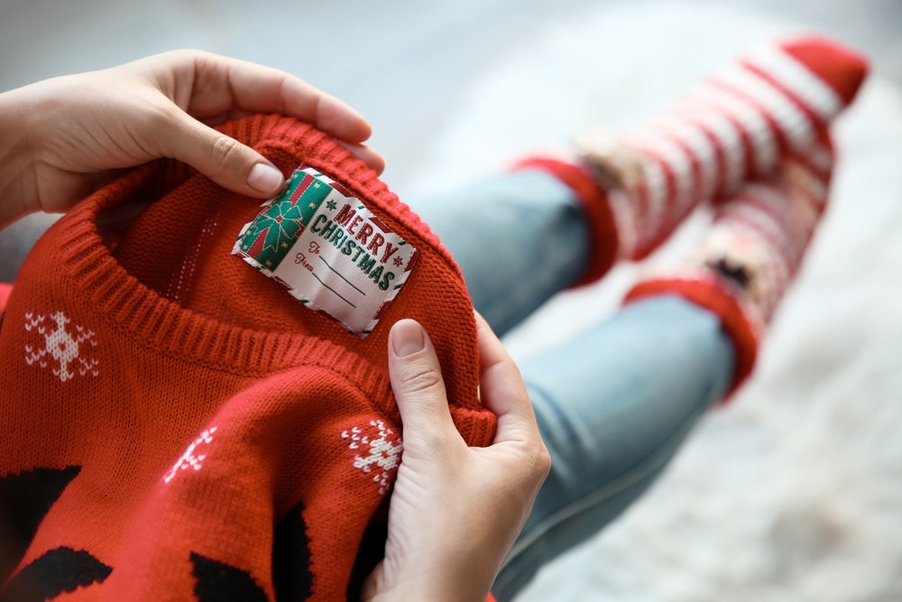Mujer observando la etiqueta de un suéter navideño. | Foto: Shutterstock