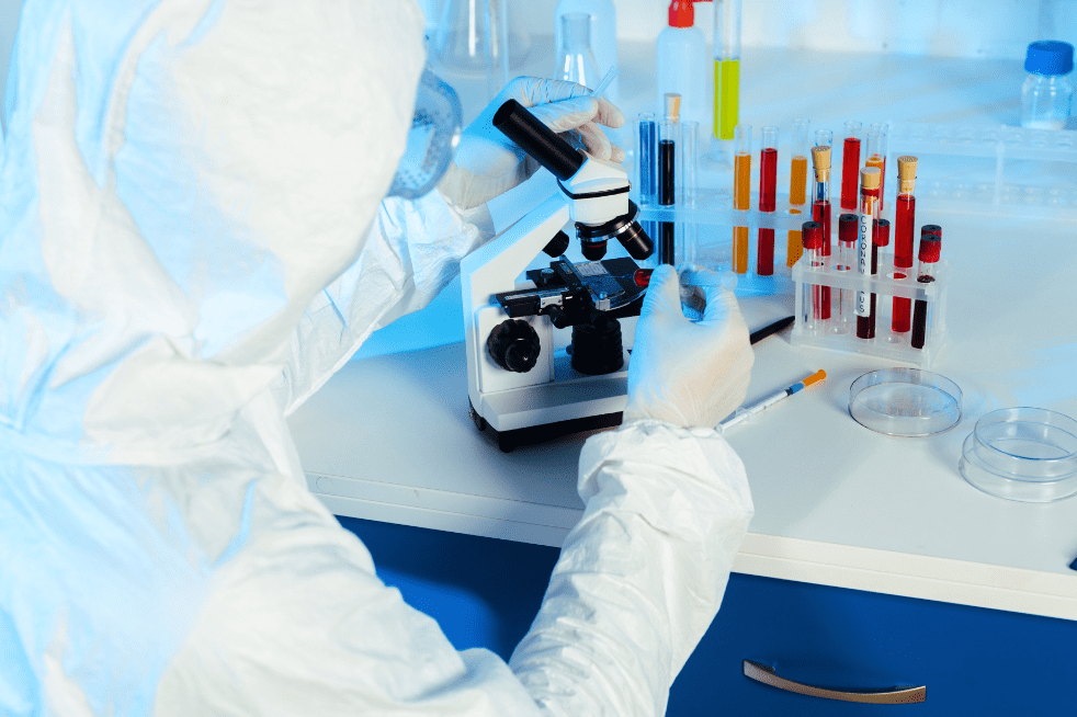 Scientist in hazmat suit near microscope in laboratory. | Source: Shutterstock