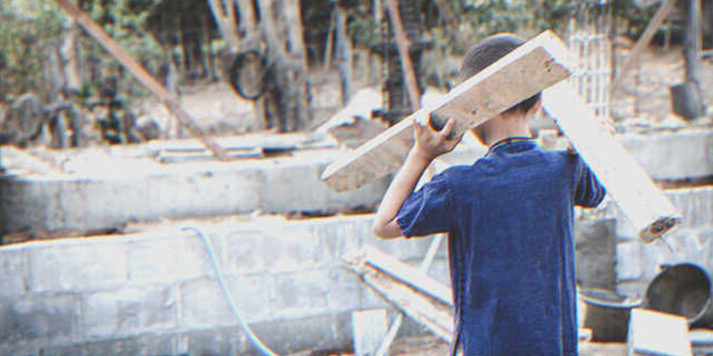 Un jeune garçon porte des planches de bois | Shutterstock