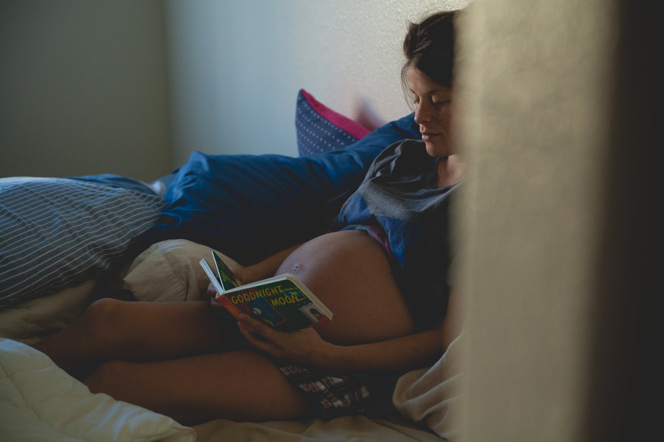 Pregnant woman reading her baby a children's book | Source: Pexels