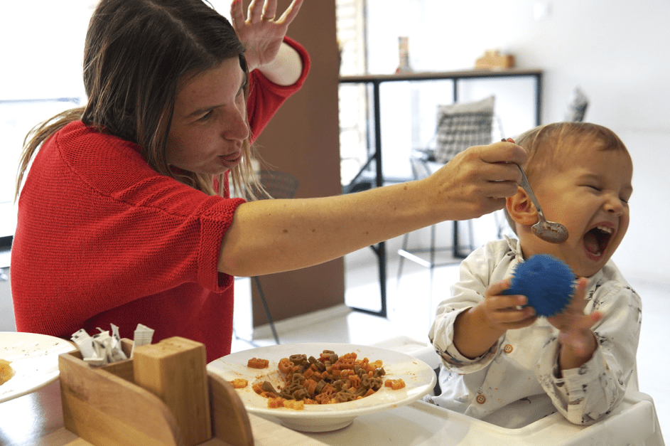 Kind weint und weigert sich im Restaurant zu essen, während Mutter versucht, es zu füttern. | Quelle: Getty Images