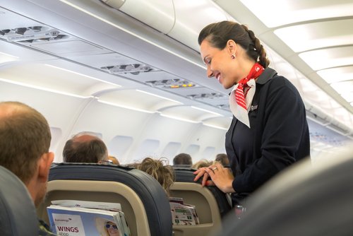 Eine Flugbegleiterin spricht mit Passagieren | Quelle: Shutterstock