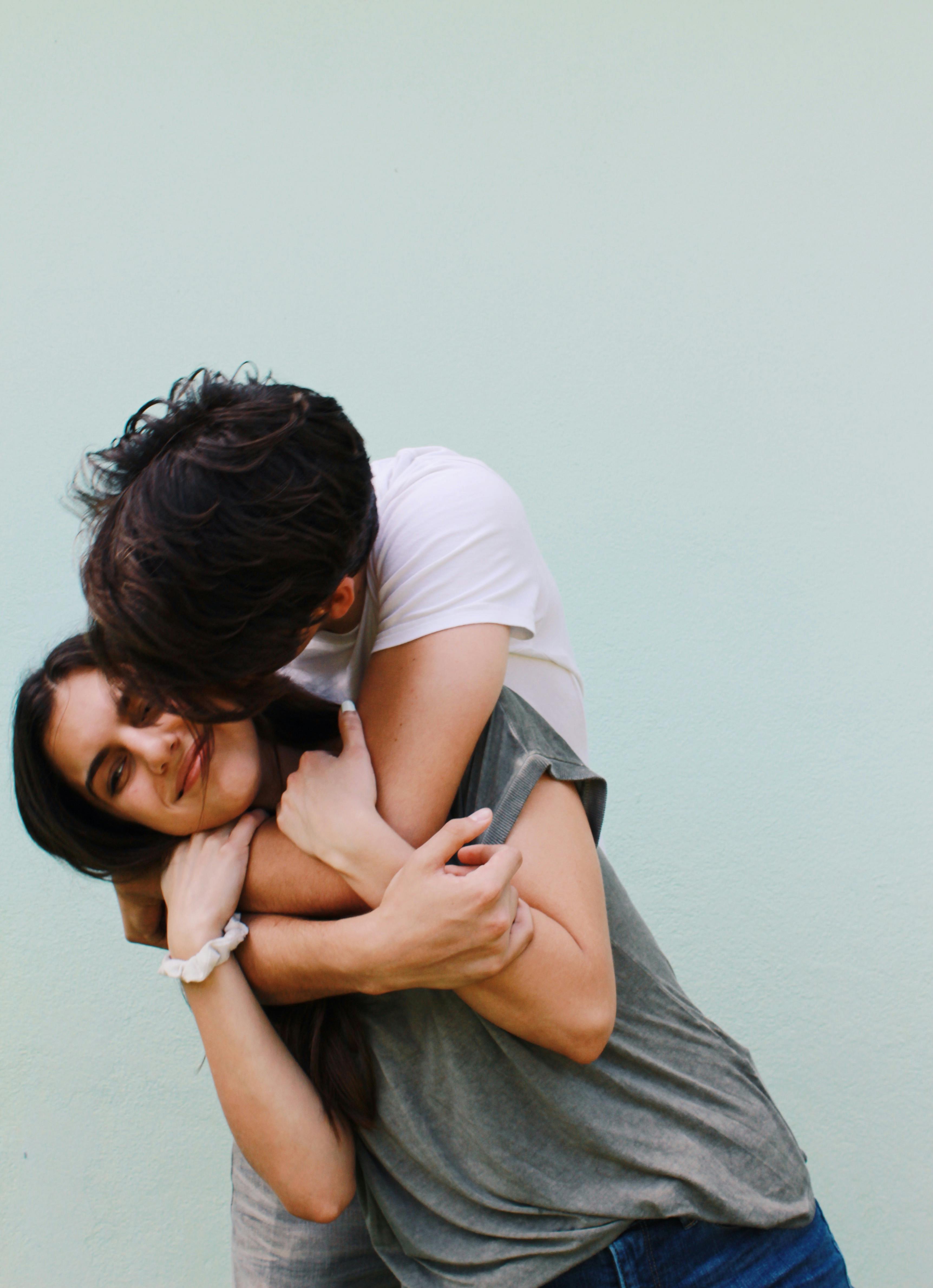 A happy man kissing and hugging a disgruntled-looking woman | Source: Pexels