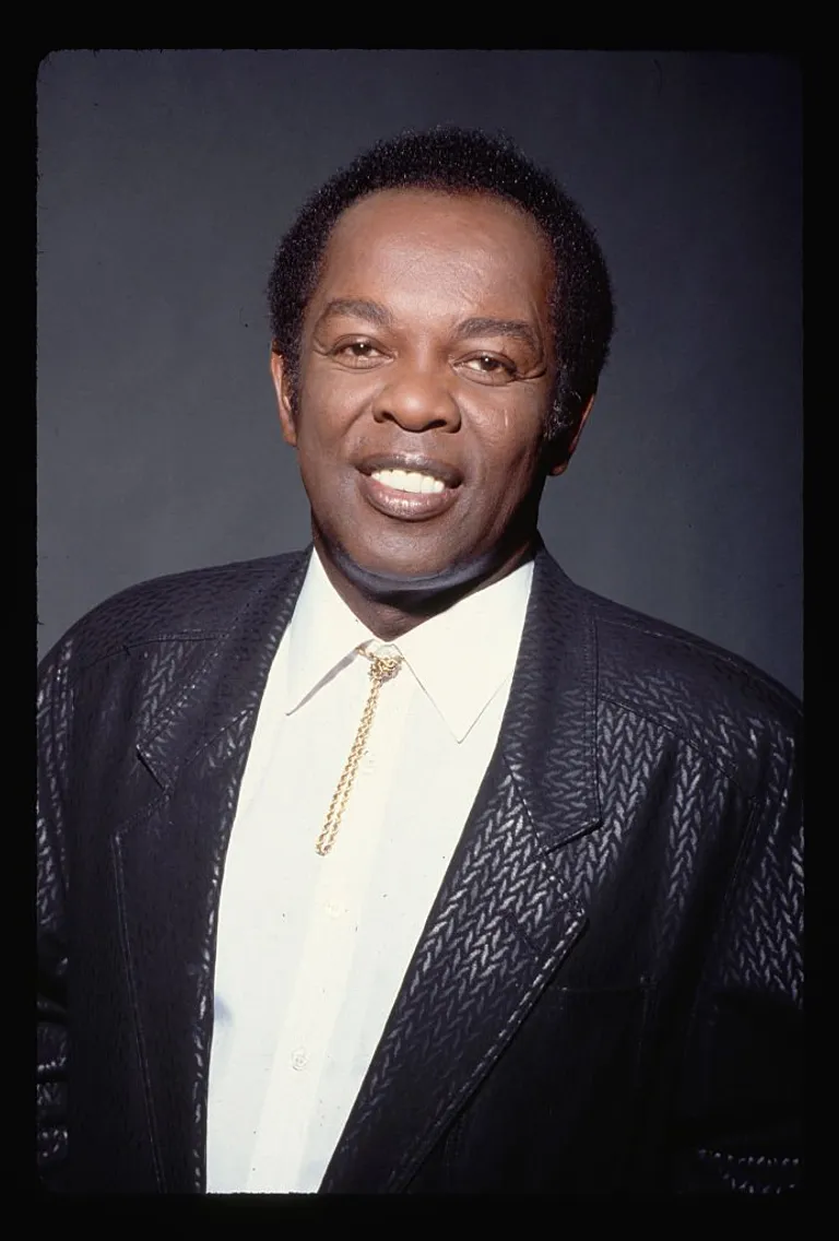 A portrait of Lou Rawls posing in a black blazer and a bolo tie around his collar. | Source: Getty Images