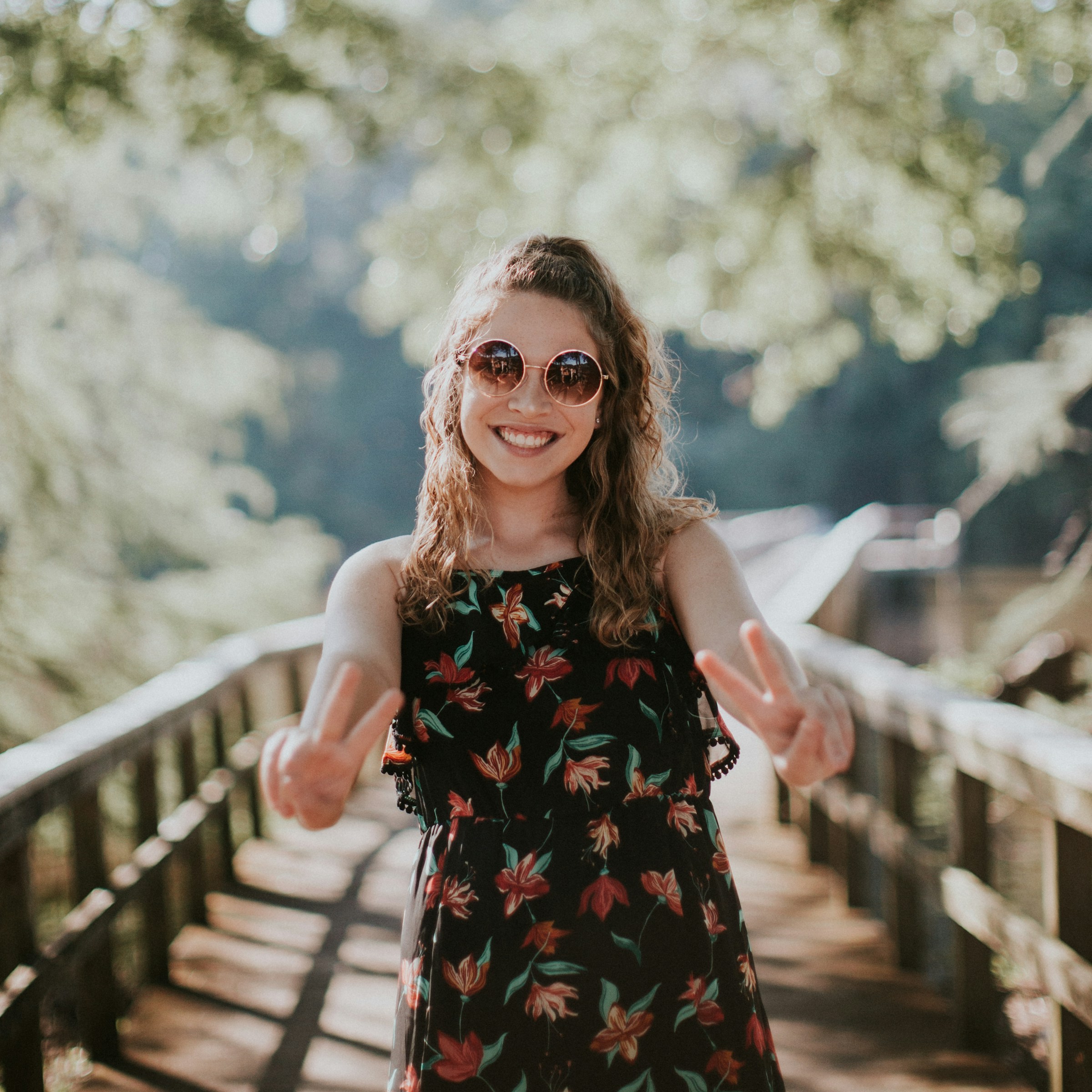 A woman smiling while making the victory sign with her hands | Source: Pexels