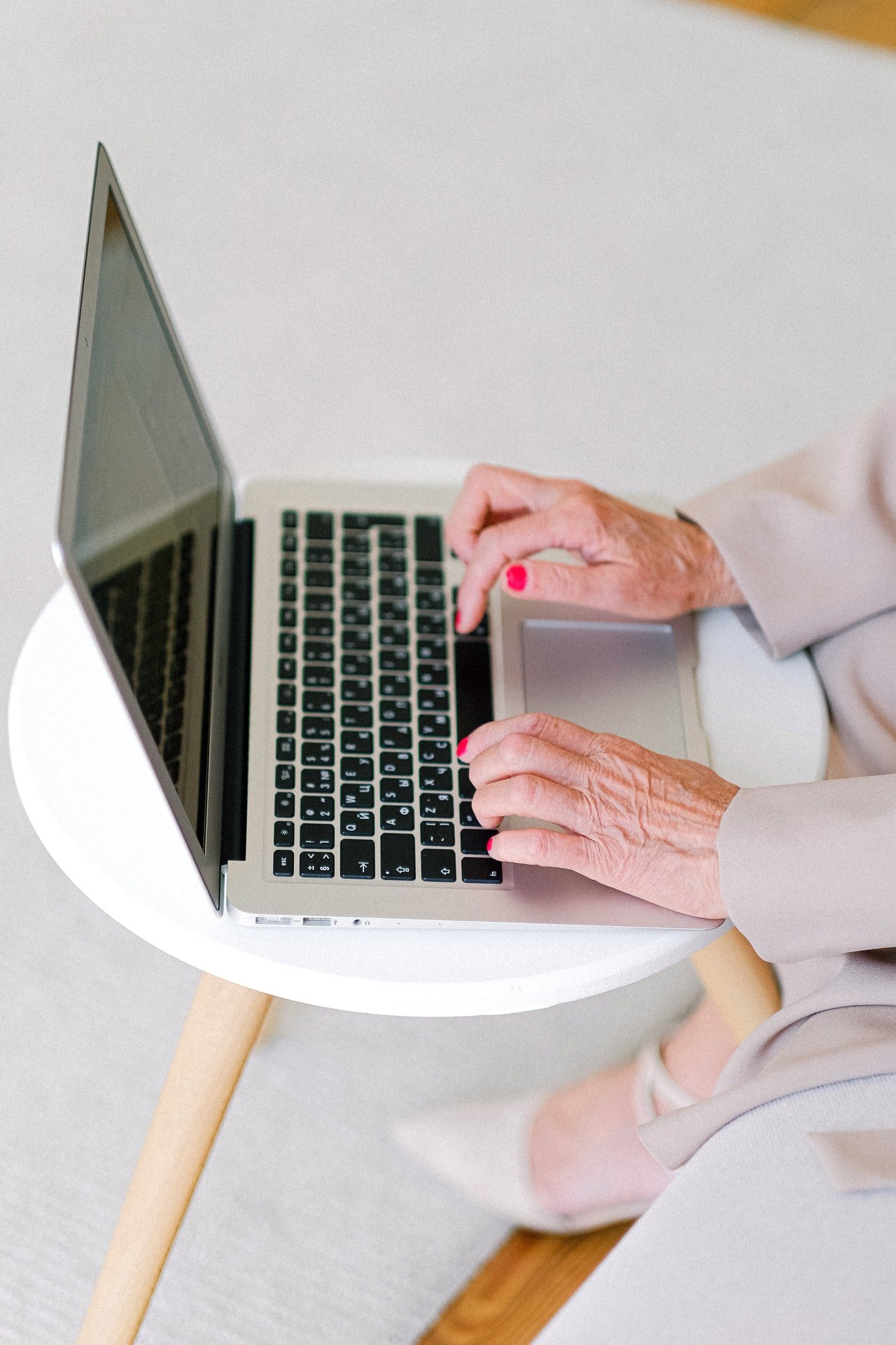 Una mujer mayor escribiendo en una computadora portátil. | Foto: Pexels