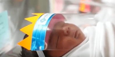 Recién nacido utilizando la "corona protectora" del centro de salud tailandés. | Foto:  YouTube /  New York Post