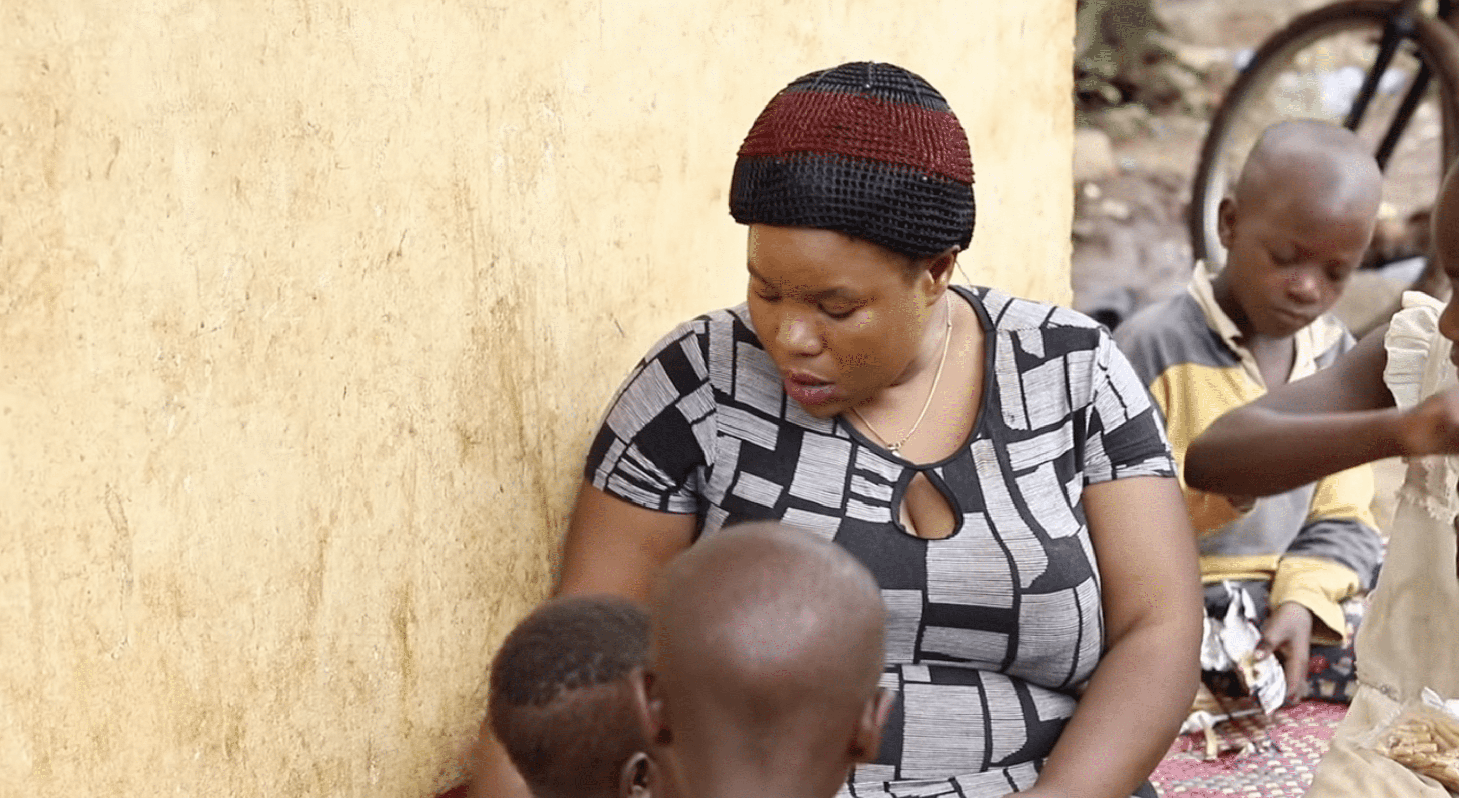 Mariam Nabatanzi sitzt mit ihren jüngeren Kindern. | Quelle: YouTube.com/Connect With Uganda