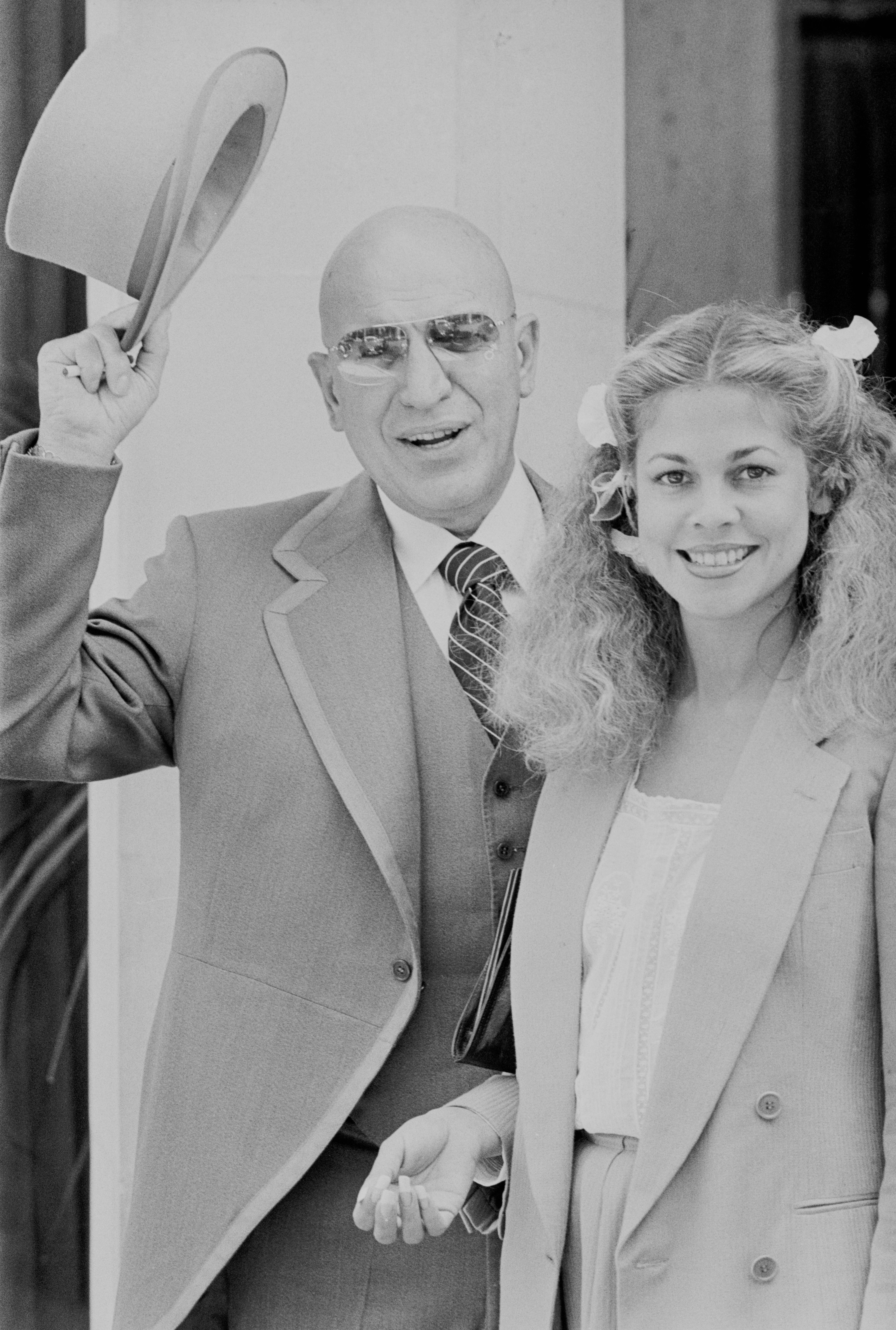 American singer and actor Telly Savalas (1922 - 1994) with girlfriend Sally Adams, UK, 20th June 1977 | Photo: Getty Images American singer and actor Telly Savalas (1922 - 1994) with girlfriend Sally Adams, UK, 20th June 1977 | Photo: Getty Images