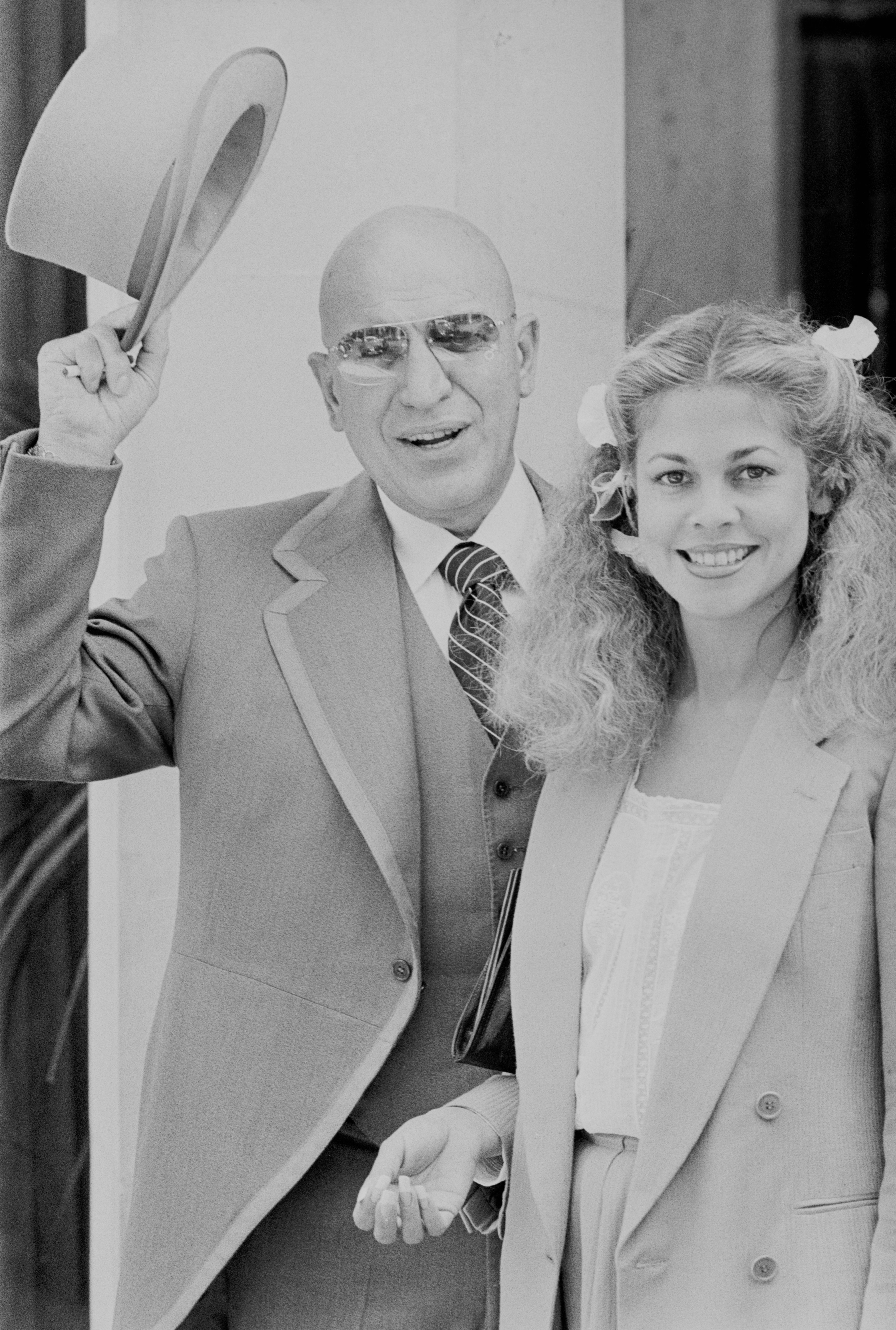 La chanteuse et actrice américaine Telly Savalas (1922 - 1994) avec sa petite amie Sally Adams, Royaume-Uni, 20 juin 1977 |  Photo: Getty Images