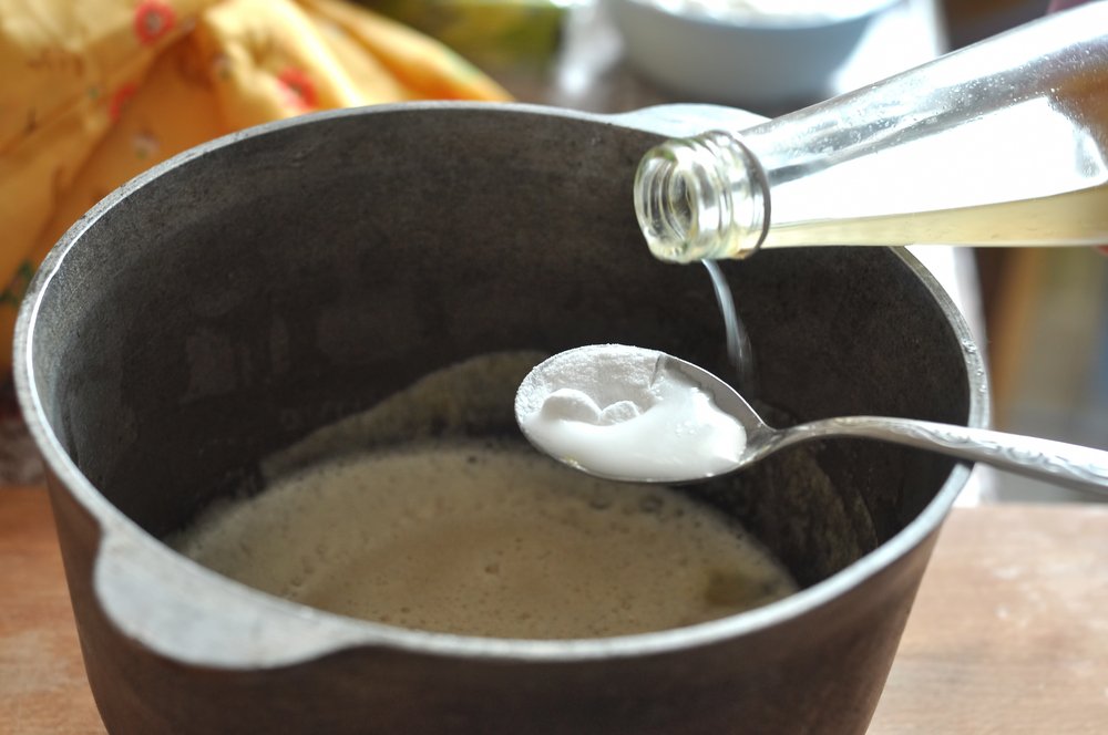 A mixture of baking soda and vinegar in a spoon over a pot. | Photo: Shutterstock