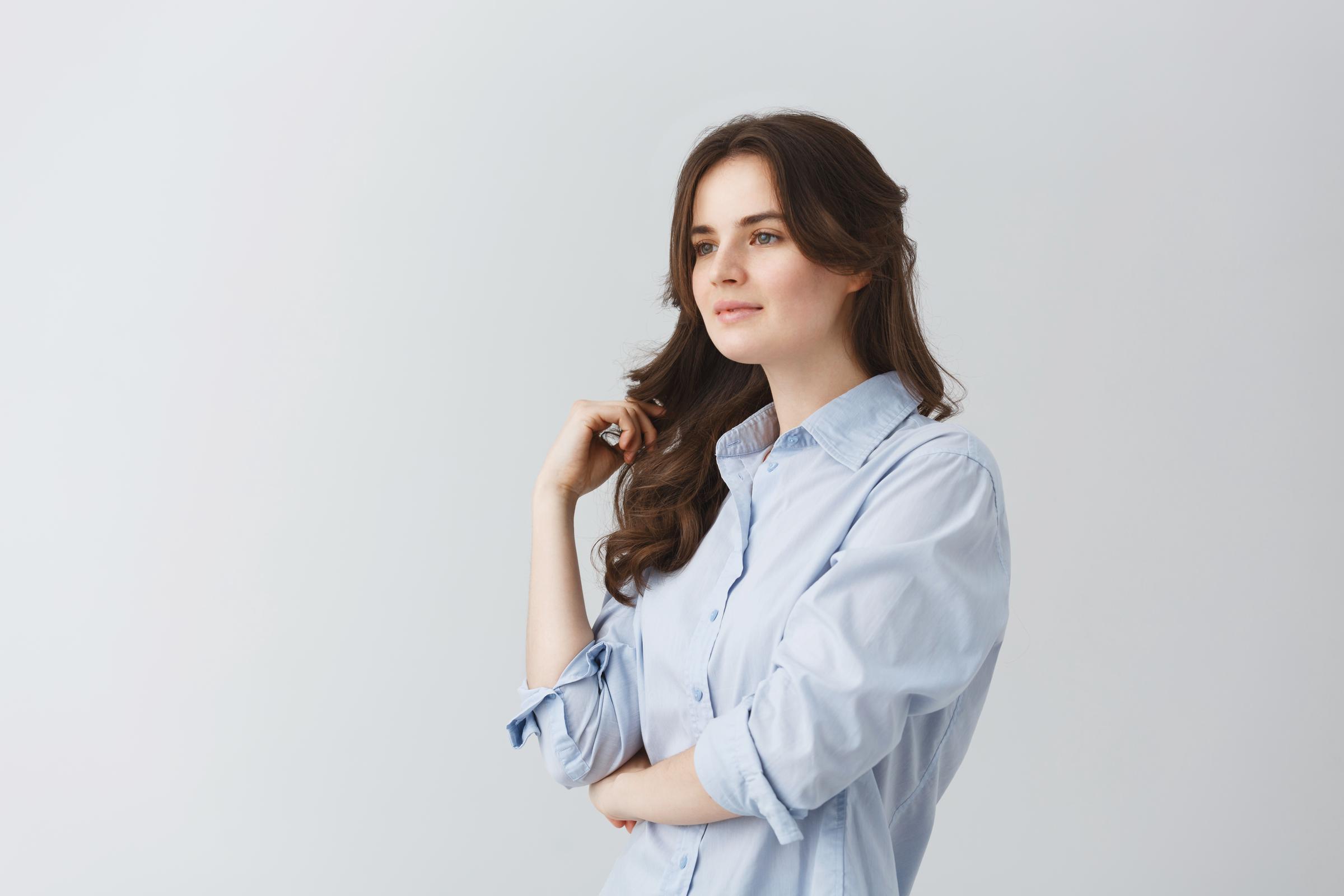 A woman touching her hair as she looks away | Source: Freepik