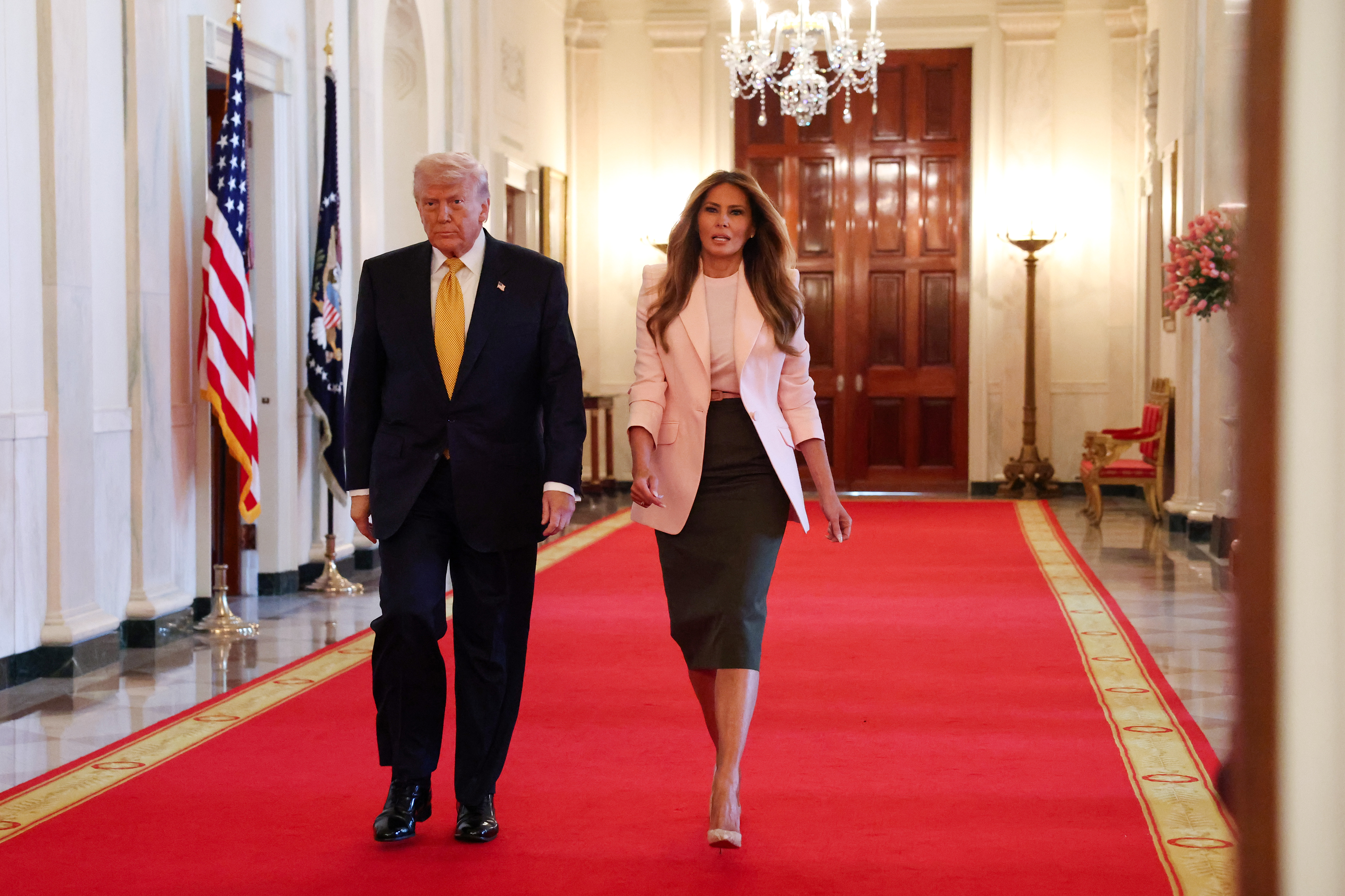 Donald Trump and Melania Trump walk down the Cross Hall as they arrive for a military mothers celebration in the East Room of the White House on May 6, 2026, in Washington, DC | Source: Getty Images