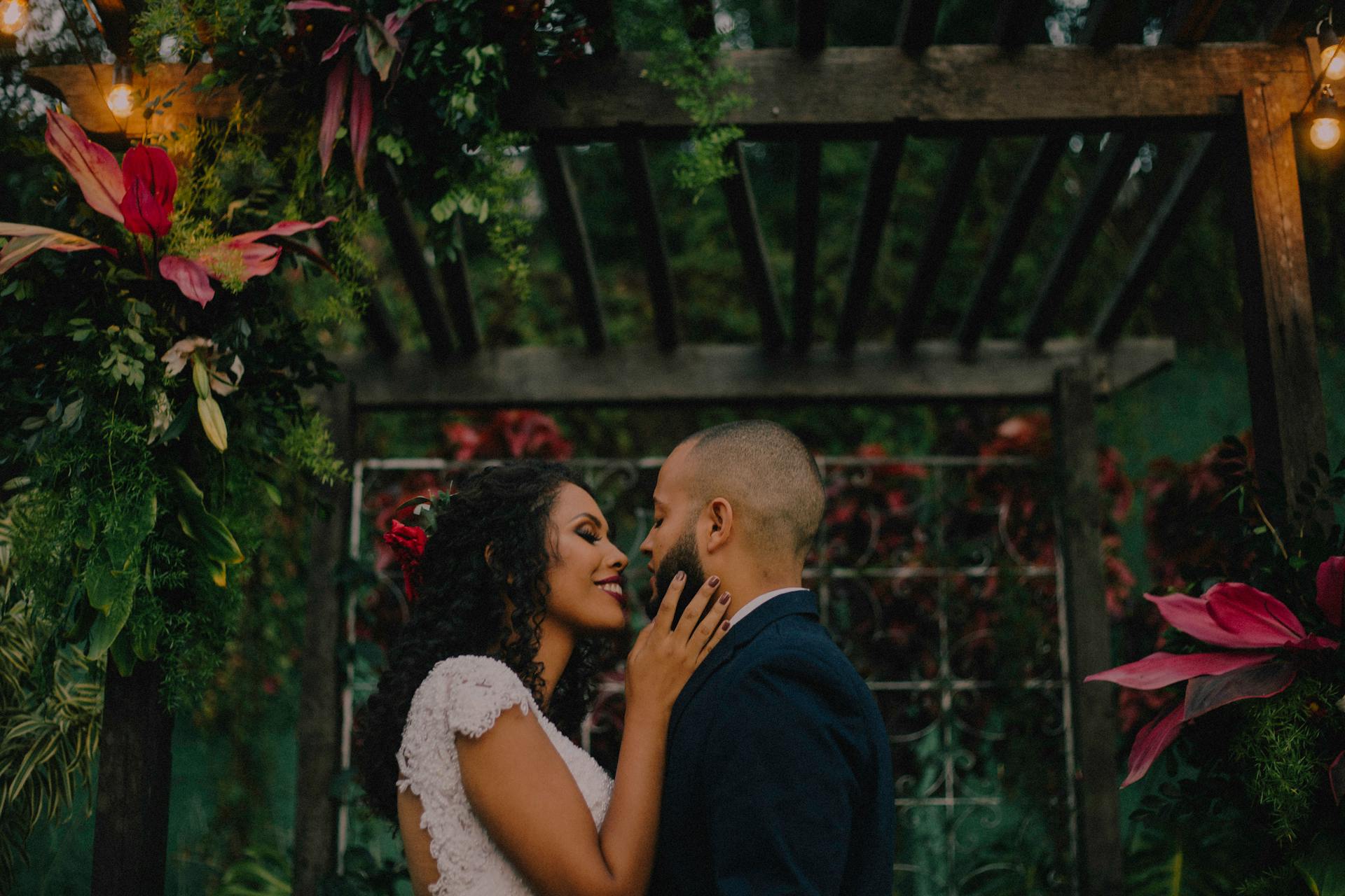 A couple standing under a garden arch covered with flowers | Source: Pexels