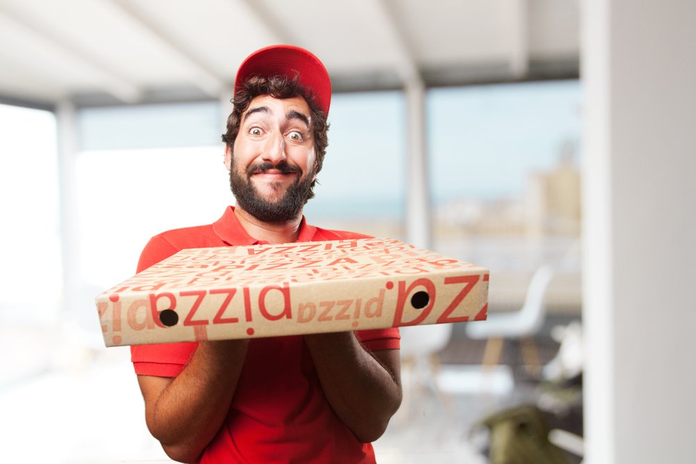 Livreur de pizza aux expressions faciales hilarantes. | Shutterstock Livreur de pizza aux expressions faciales hilarantes. | Shutterstock