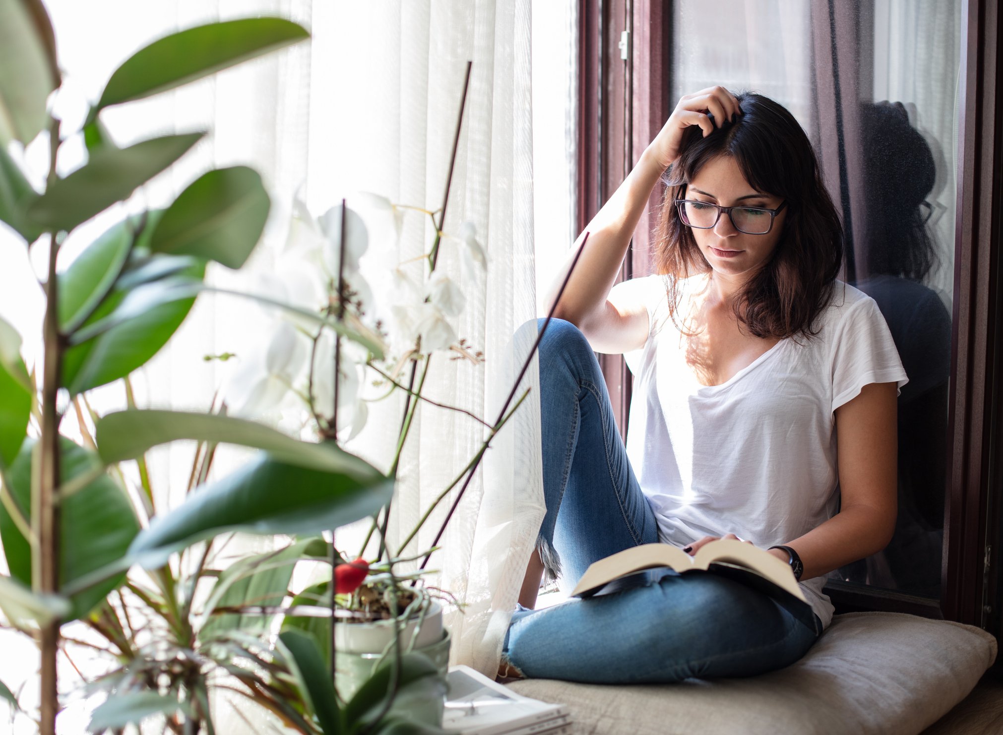 Une femme qui bouqine devant une plante | source : Getty Images