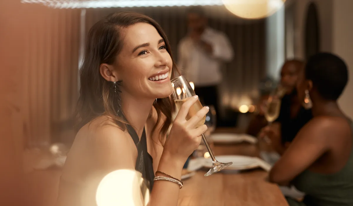 Una mujer sosteniendo una copa de champán en un restaurante | Fuente: Shutterstock