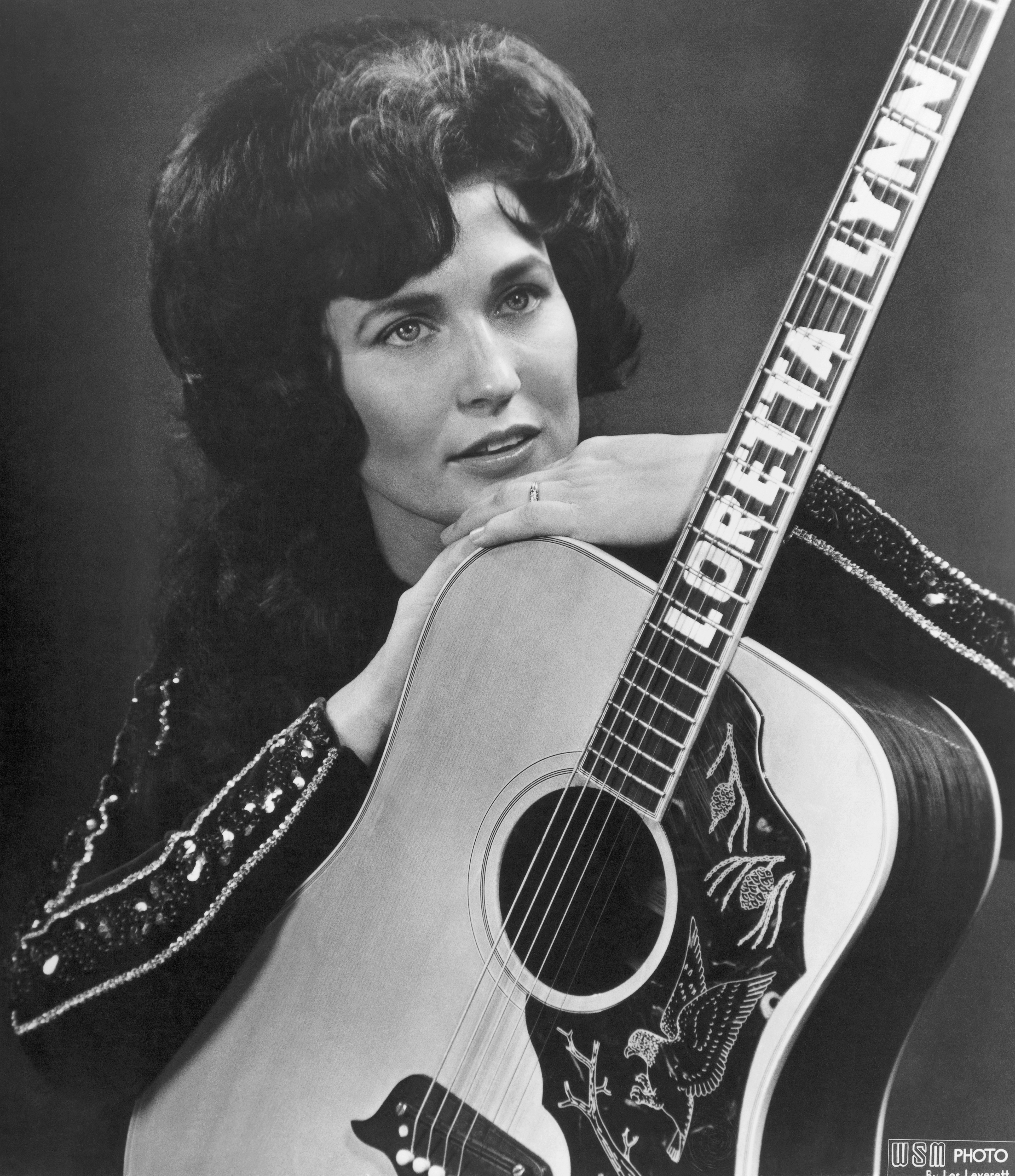 Loretta Lynn poses for a portrait holding a guitar that has her name spelled down the fretboard in Nashville, Tennessee, in 1961. | Source: Getty Images