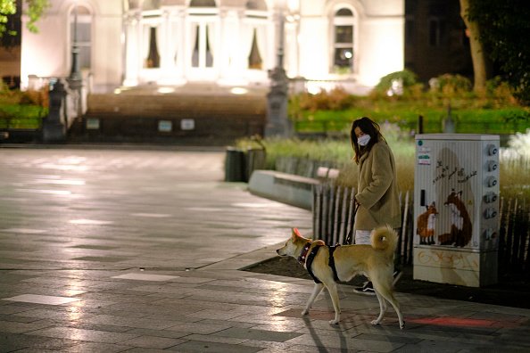 Frau geht mit ihrem Hund und MNS spazieren, Belgien, 20. Oktober 2020 | Quelle: Getty Images