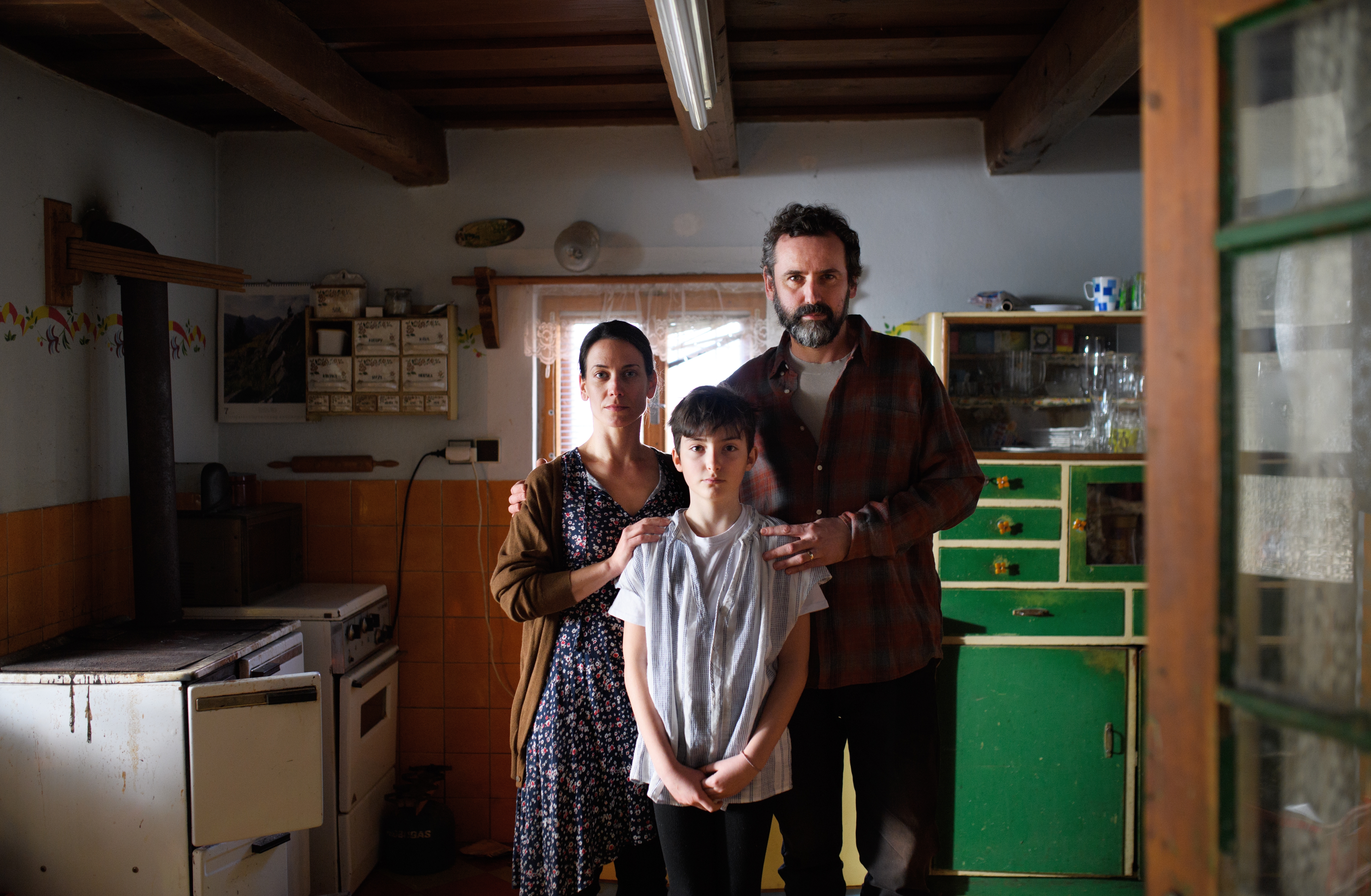 A family of three standing in the kitchen | Source: Shutterstock