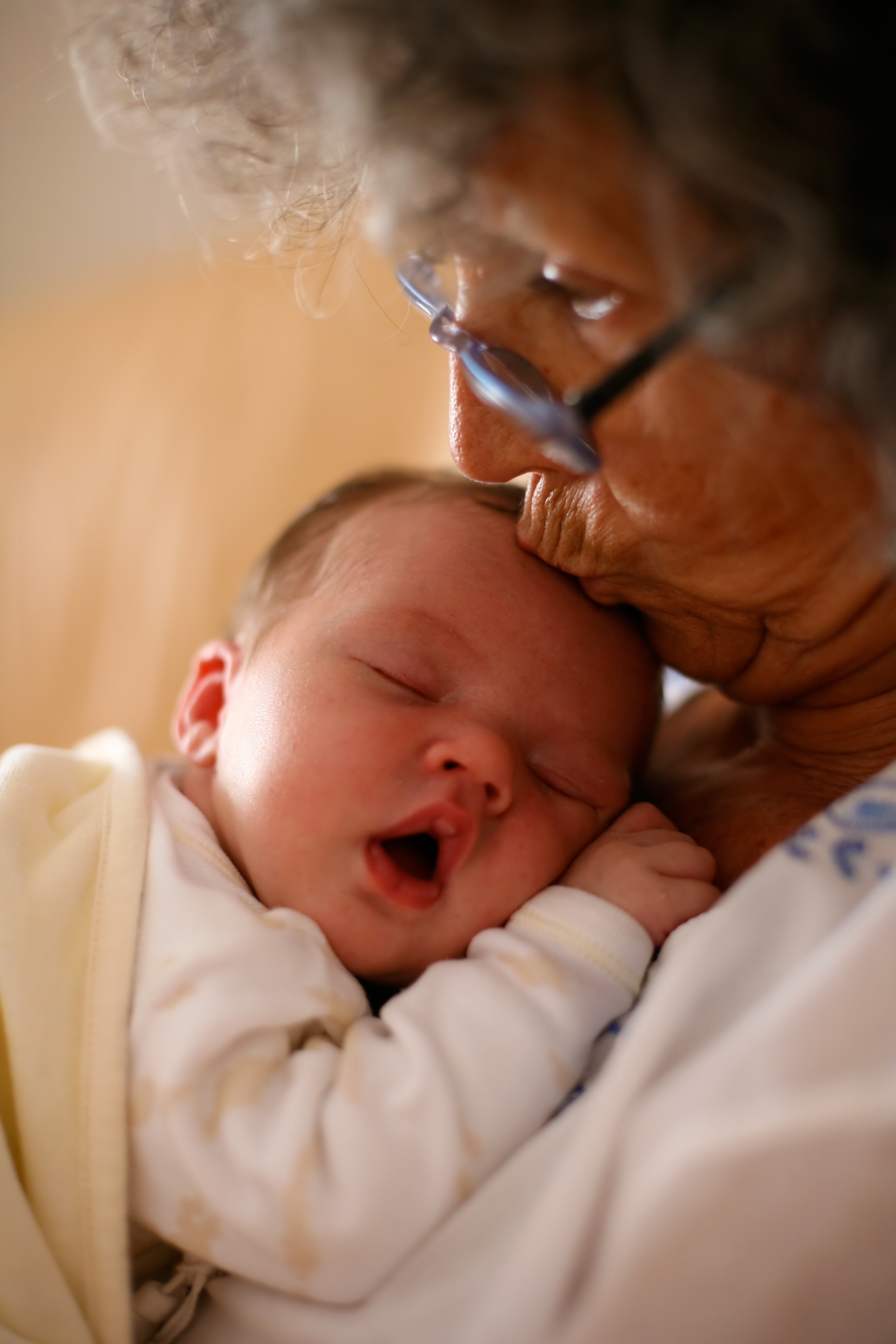 Grandma holding a baby and kissing it on it's head. | Source: Shutterstock