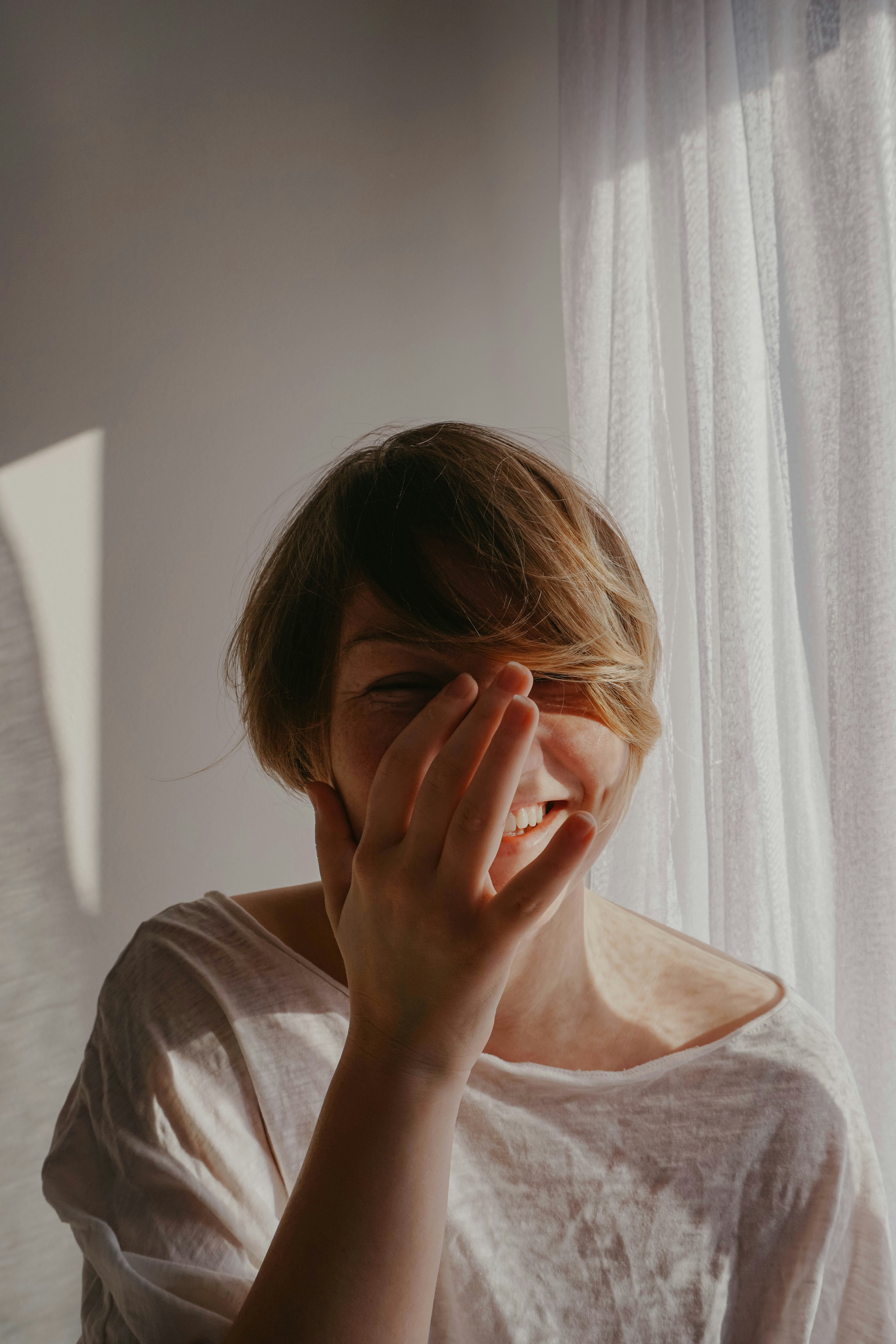 A woman covering her mouth and face while laughing | Source: Unsplash